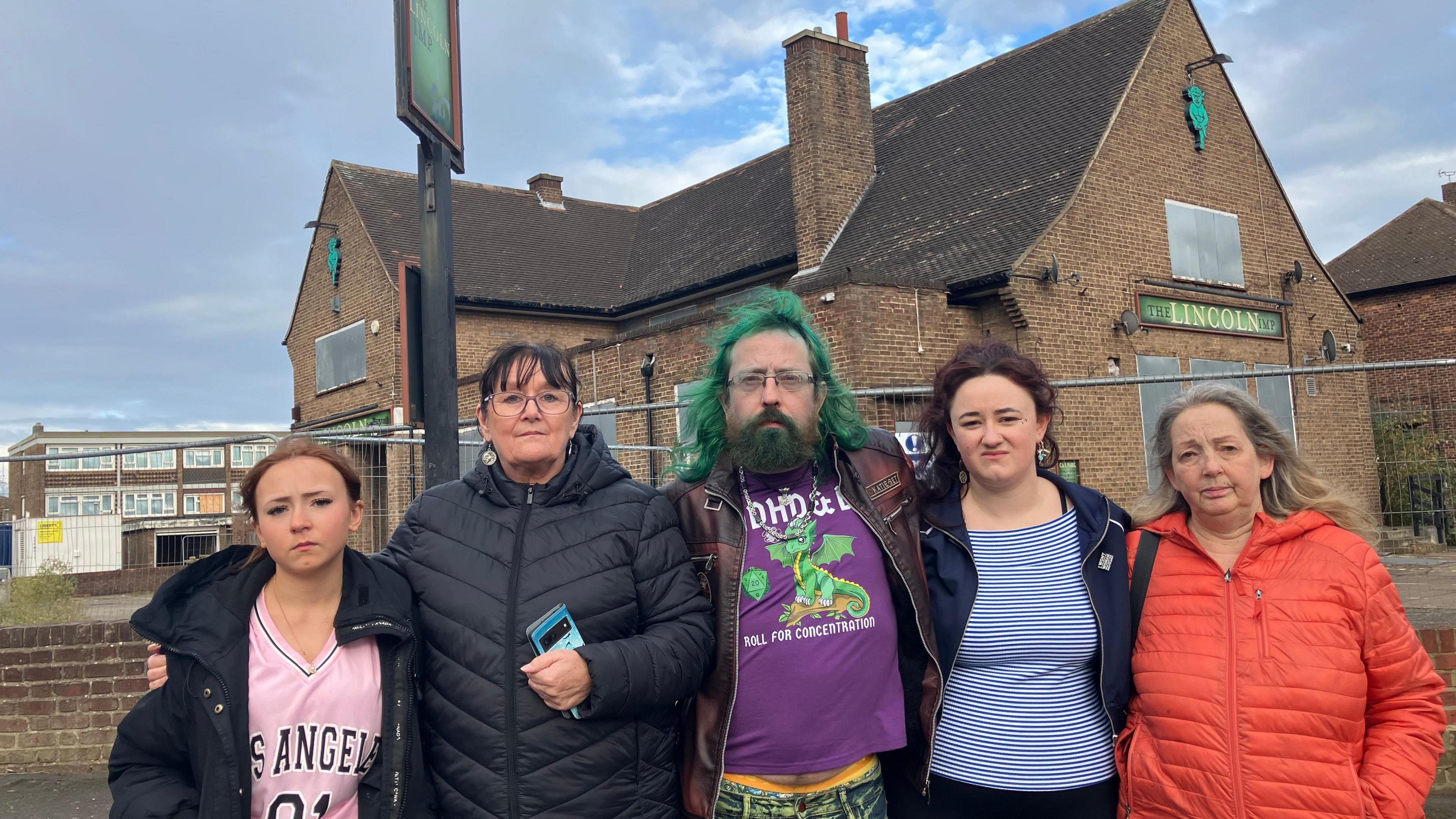 Five people standing in front of a derelict pub, the Lincoln Imp. There are three women, one man and a girl.