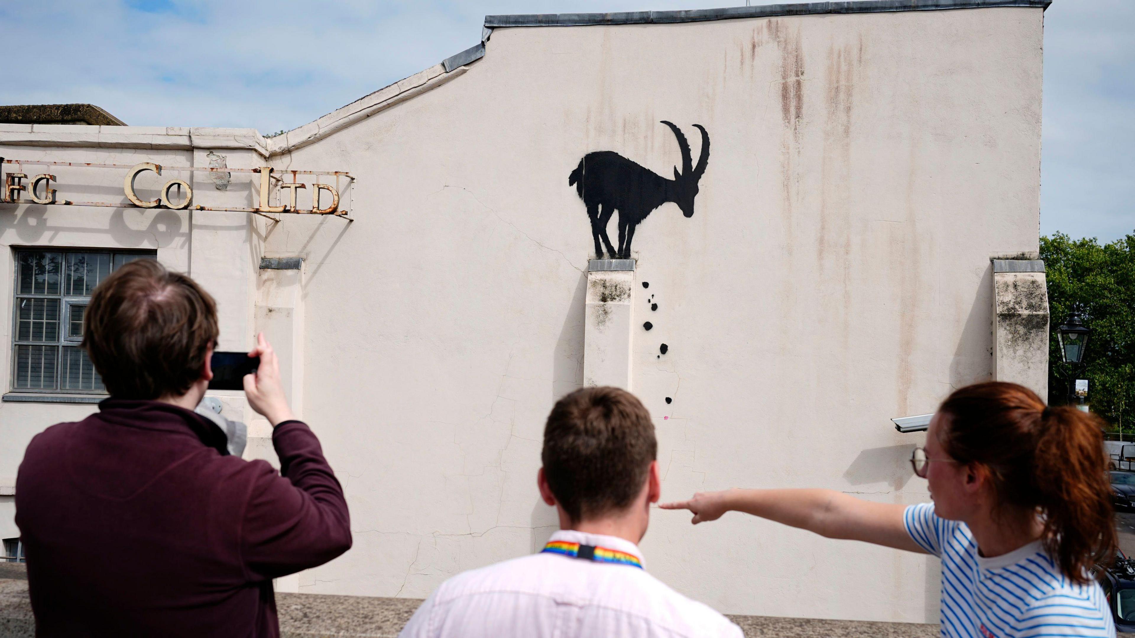 Onlookers taking pictures of the Banksy artwork