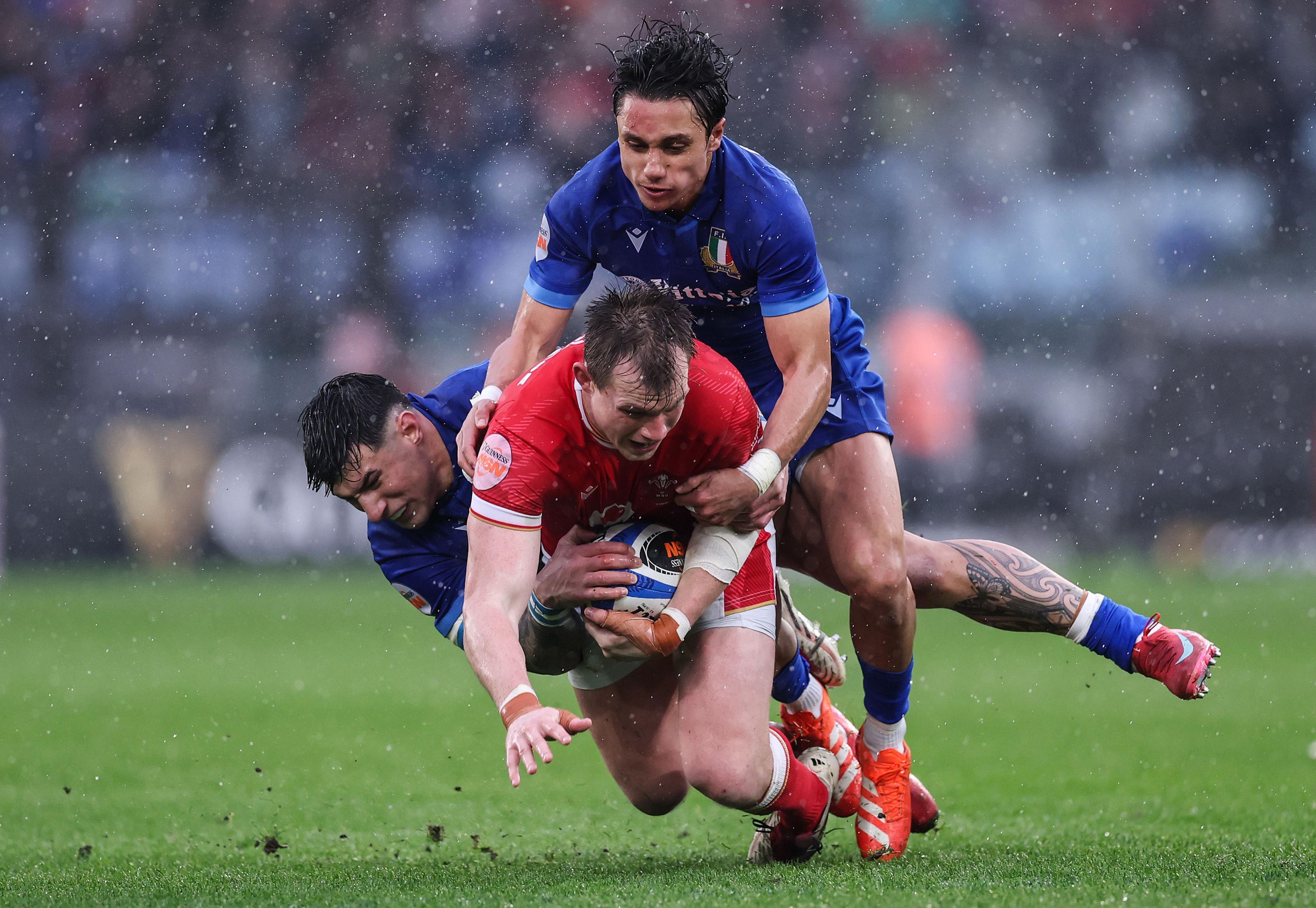 Nick Tompkins of Wales is tackled by Ange Capuozzo and Tommaso Menoncello during the Guinness Six Nations 2025 match between Italy and Wales at Stadio Olimpico in Rome, Italy