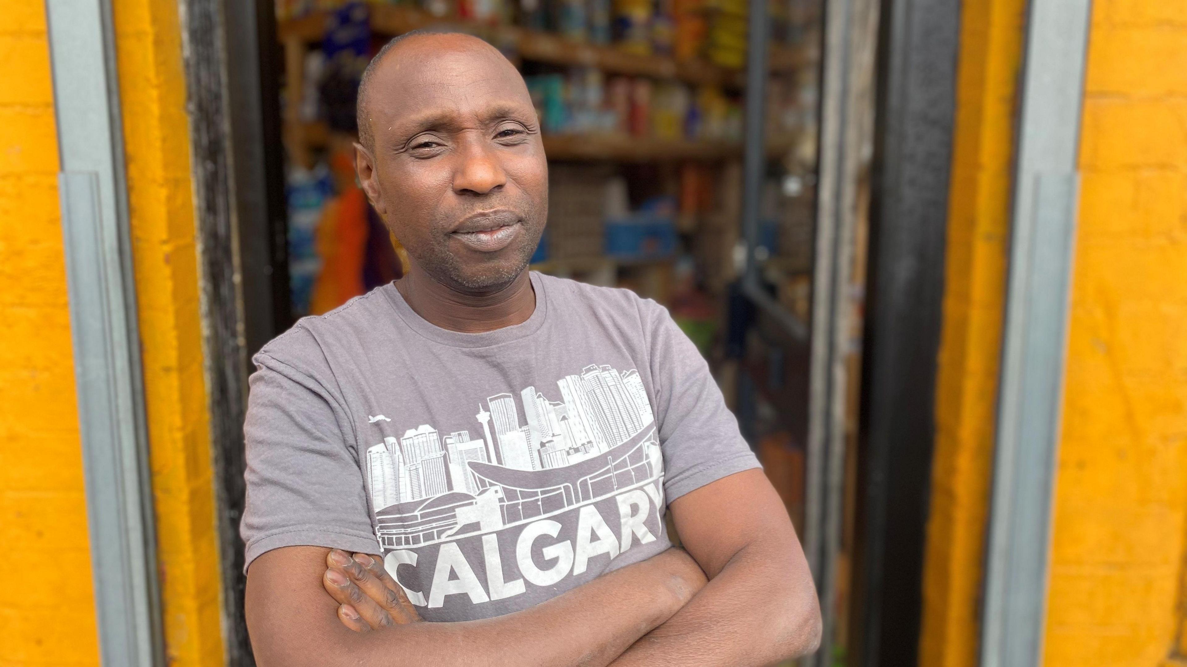 Shopkeeper Miller Kadiri wearing a grey t-shirt and stood in the doorway to his store in Harehills. 