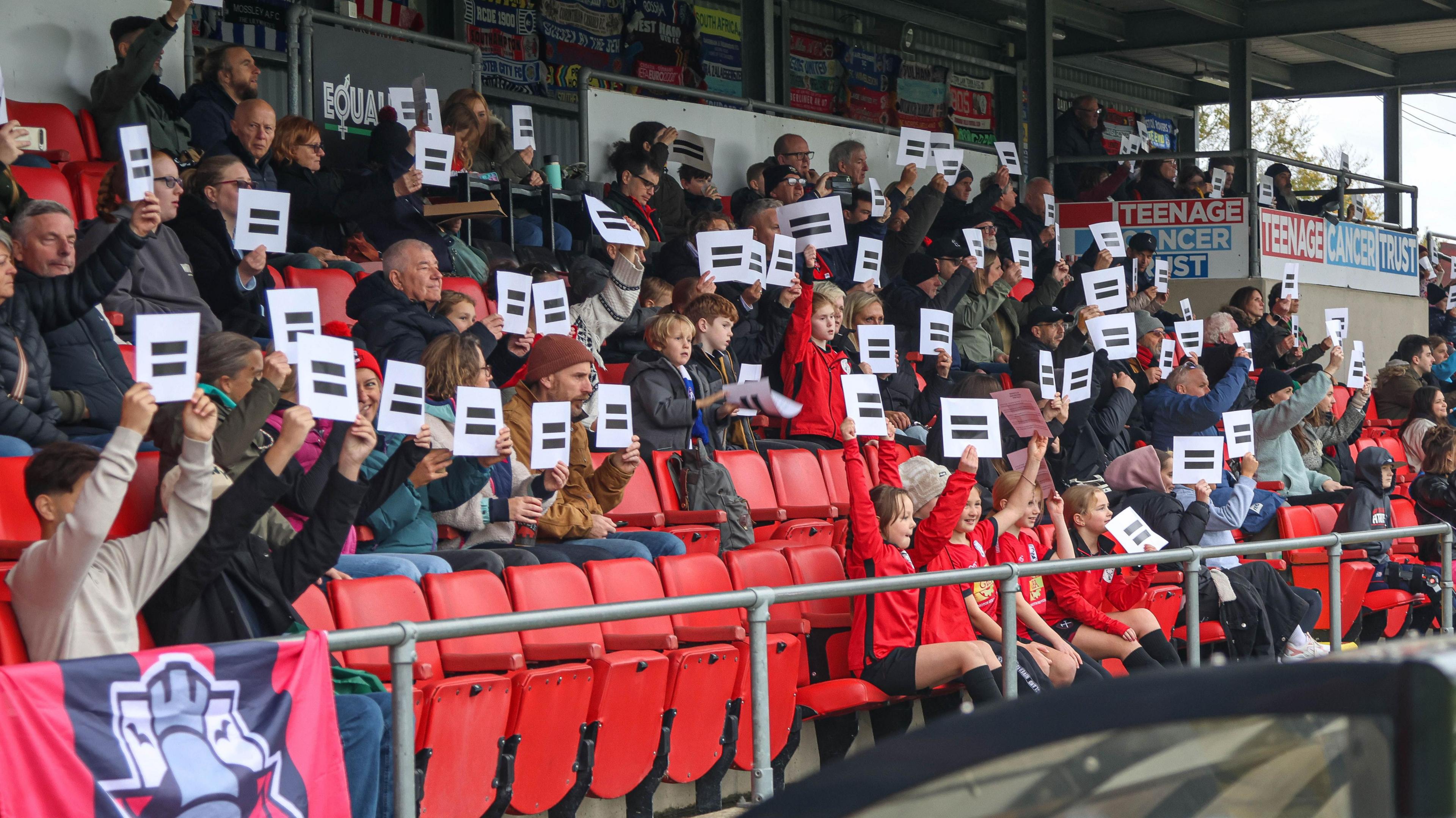 Lewes FC fans holding up 'equals' signs during their side's first-round win over Corsham Town