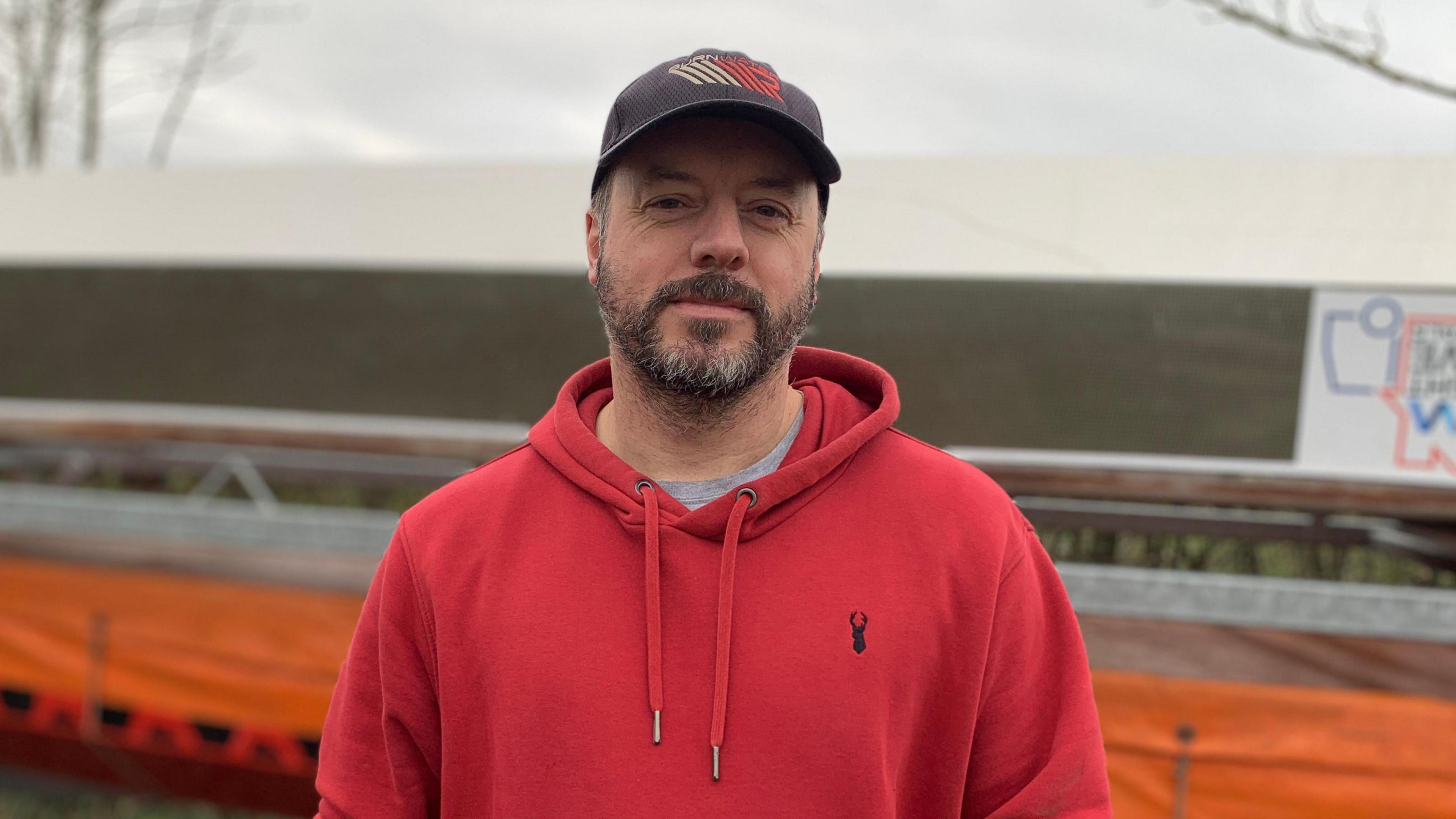 Paul Freemantle the Soaring Dragon's head coach, wearing a red hoody and a cap