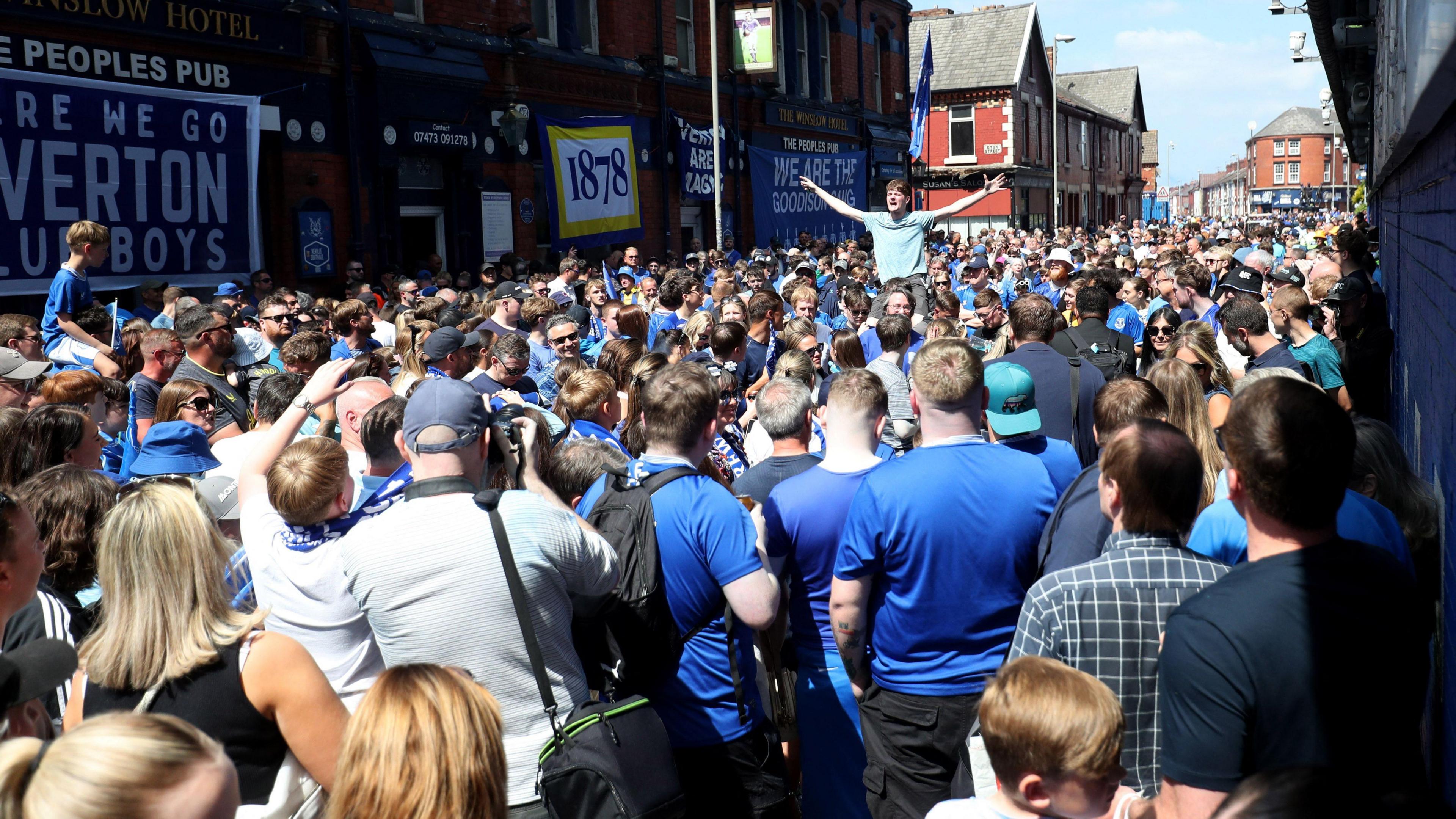 A large crowd gathers, covering an entire street