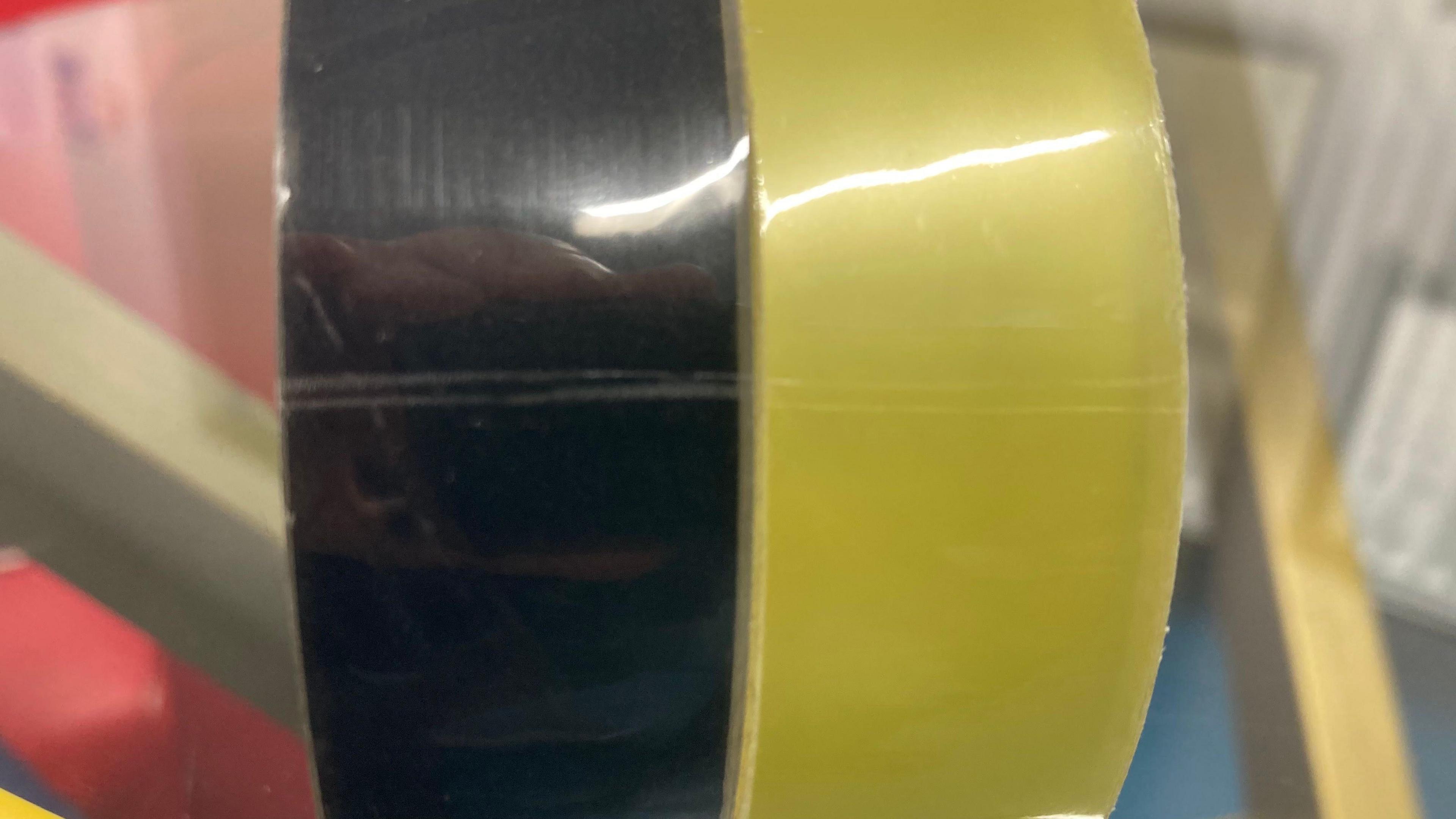 Two sticky tapes side by side, both cut at the same point. On the left Dr Bhojwani's with a cut agains a dark background and on the right a usual brand of stick tape cut at the same point