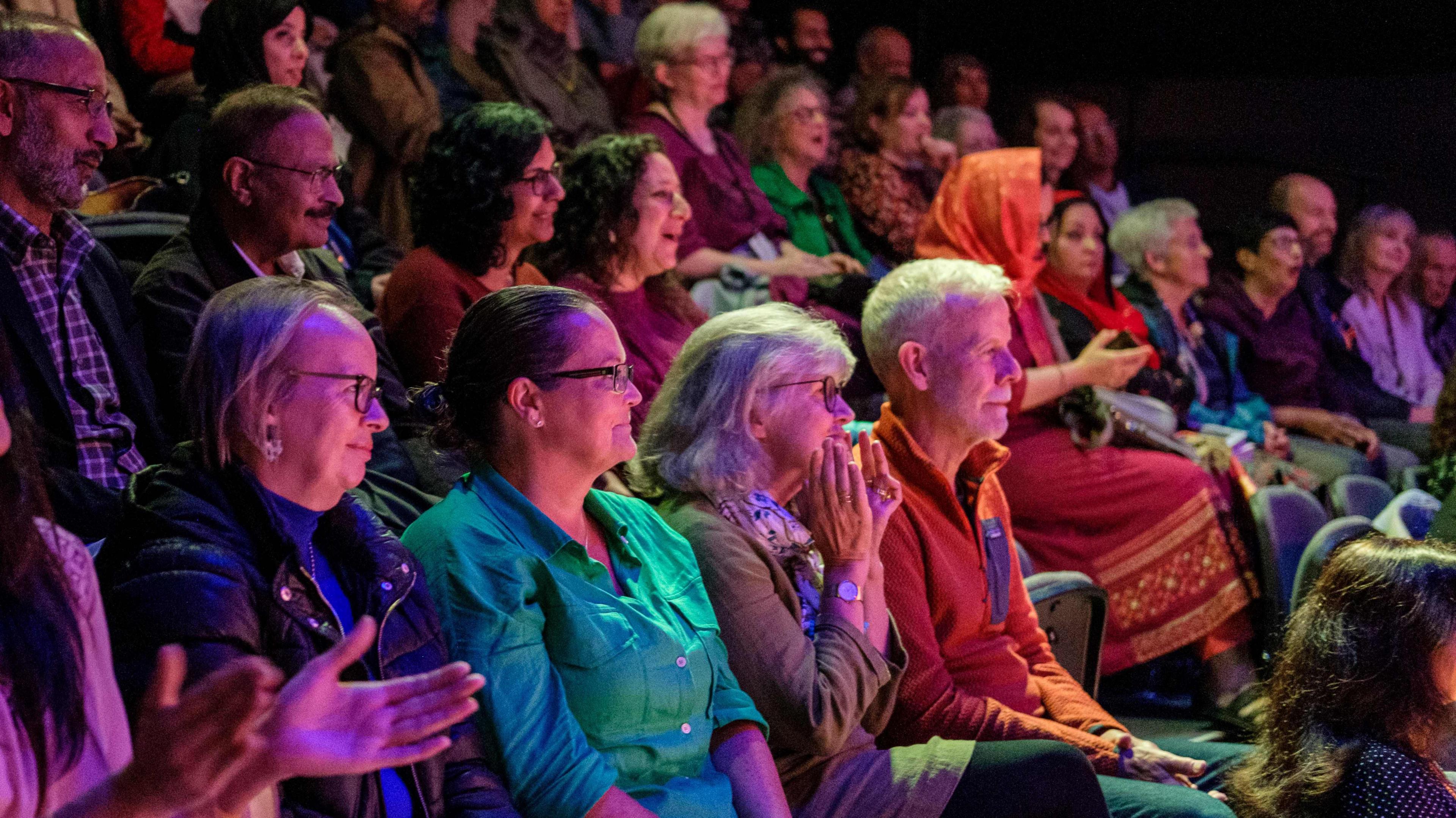 People clapping while sitting in an audience