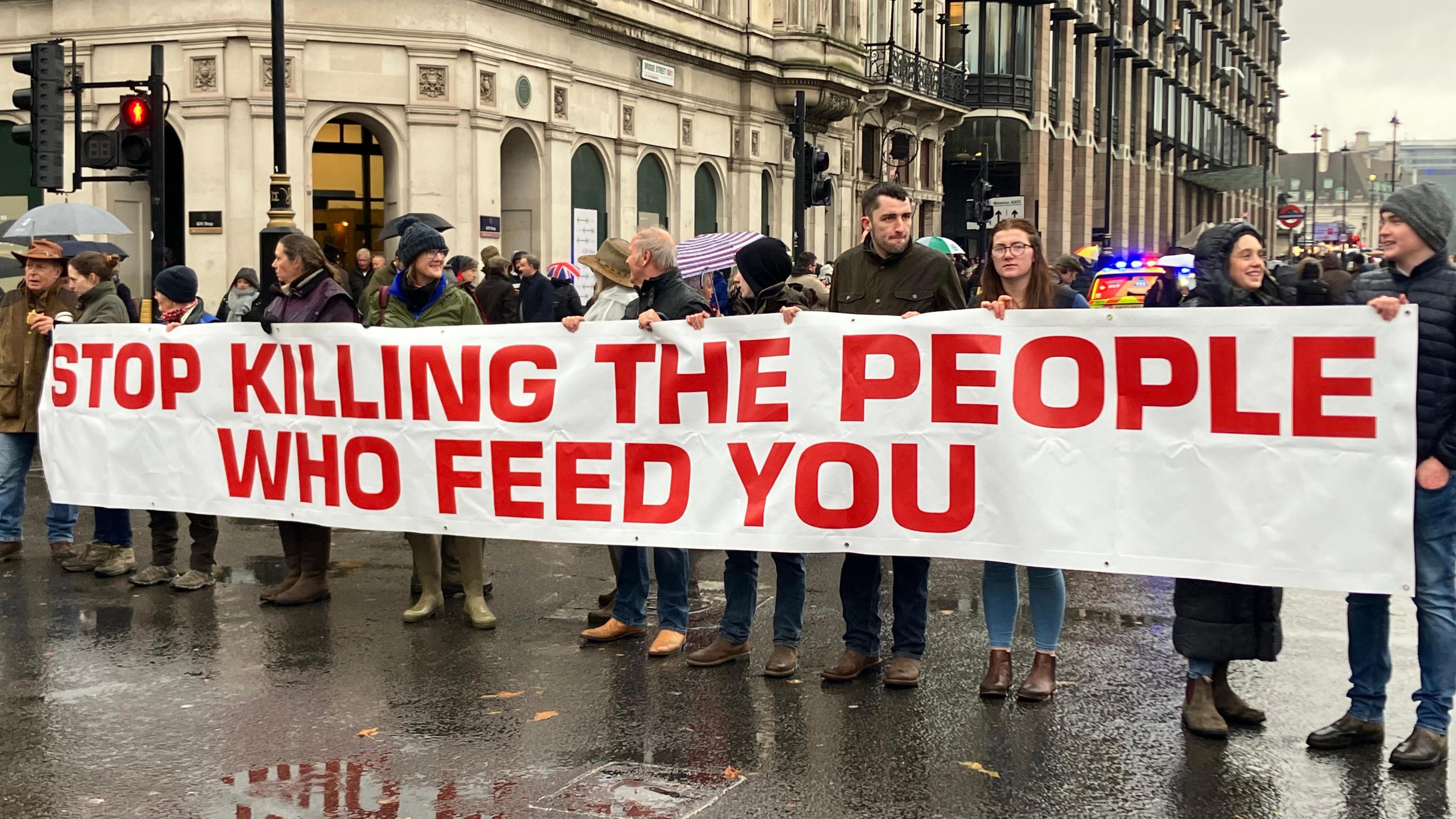 People holding a banner saying "Stop killing the people who feed you". 