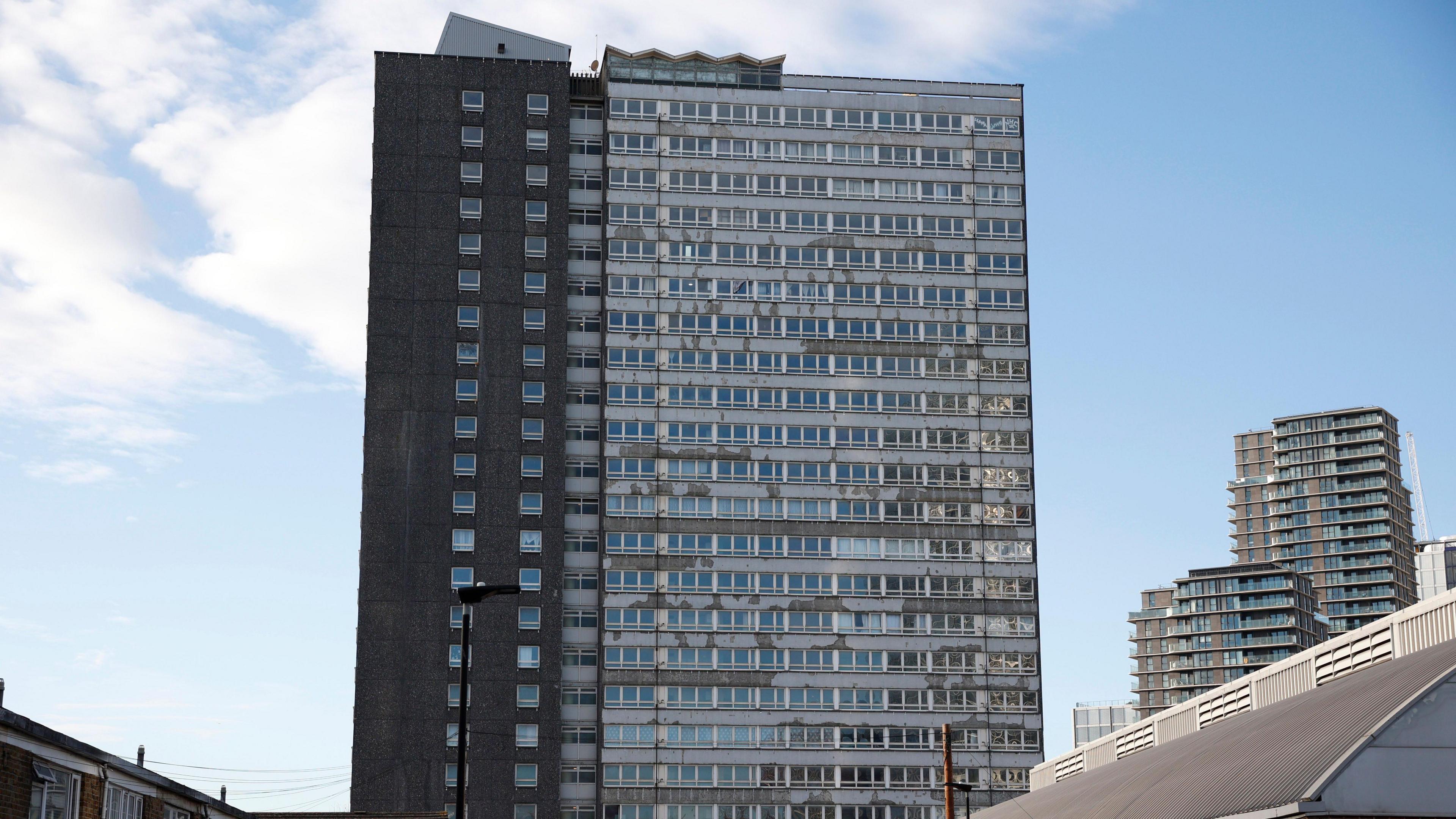 Dennison Point on the Carpenters Estate, a large pebble-dashed tower block looking fairly dilapidated with peeling paint on the outside of window frames