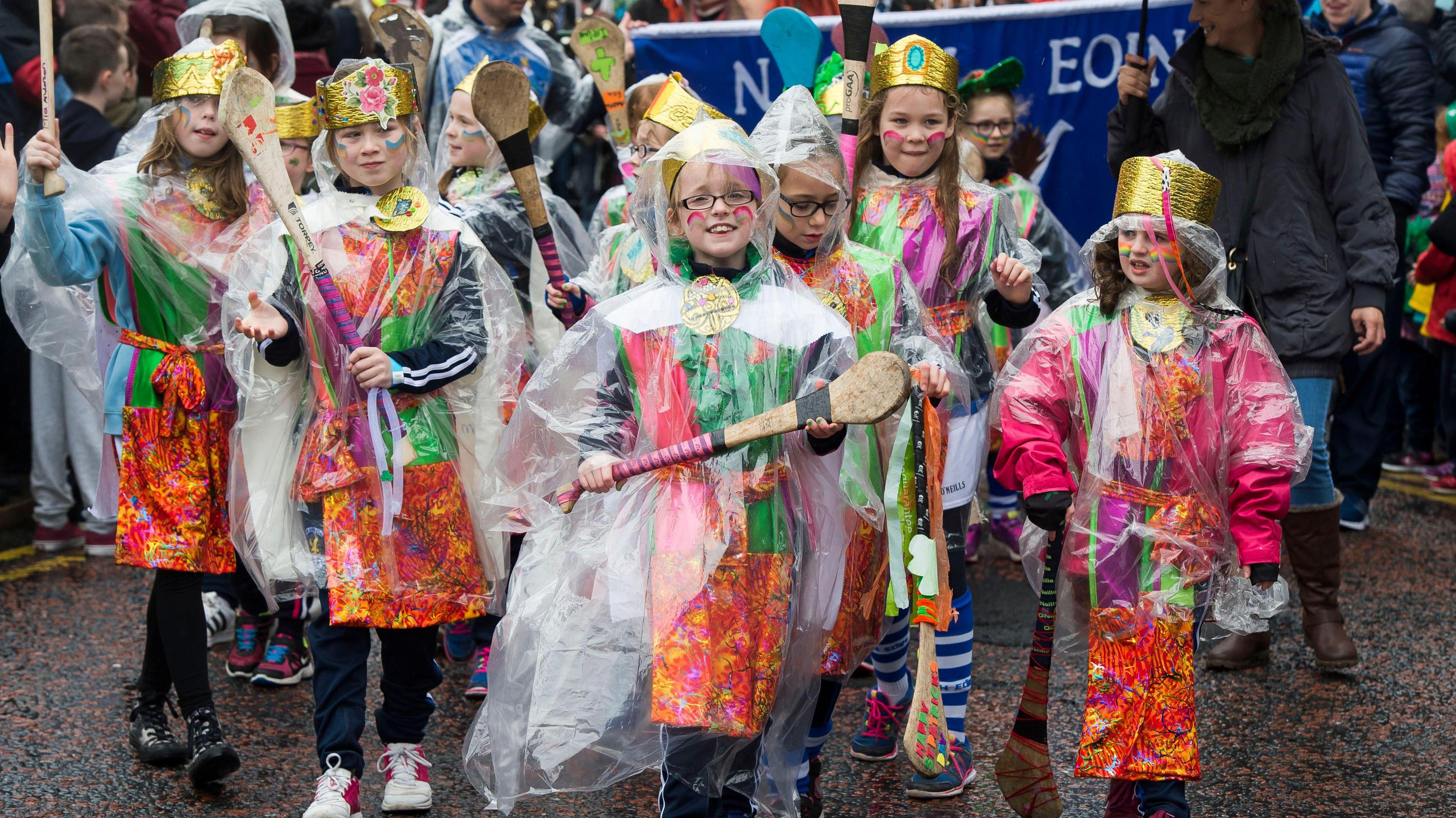 Children taking part in St Patrick's Day parades wearing see-through rain ponchos. 