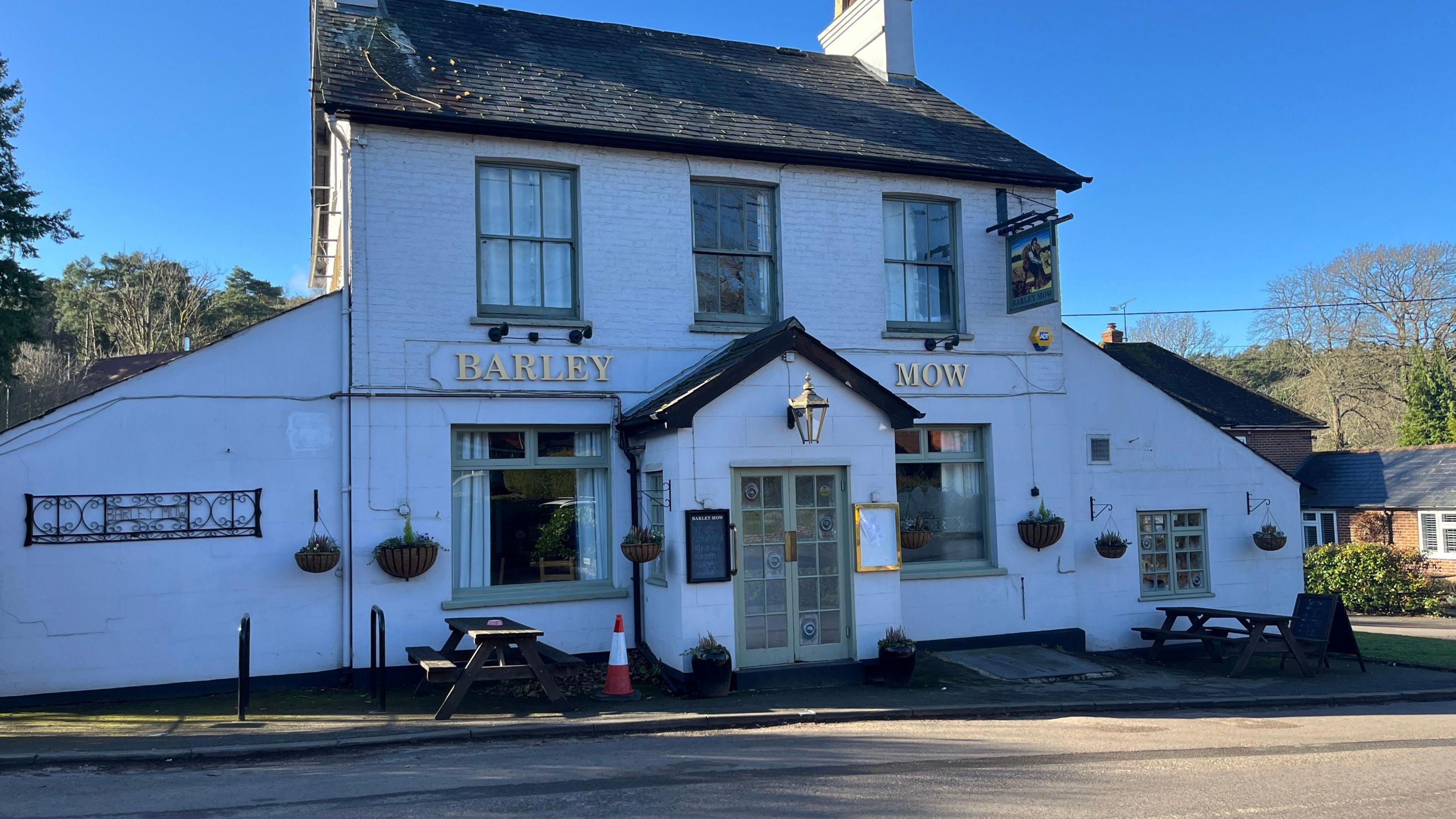 A pub by the road, with a witch's hat in the front, under clear blue skies.