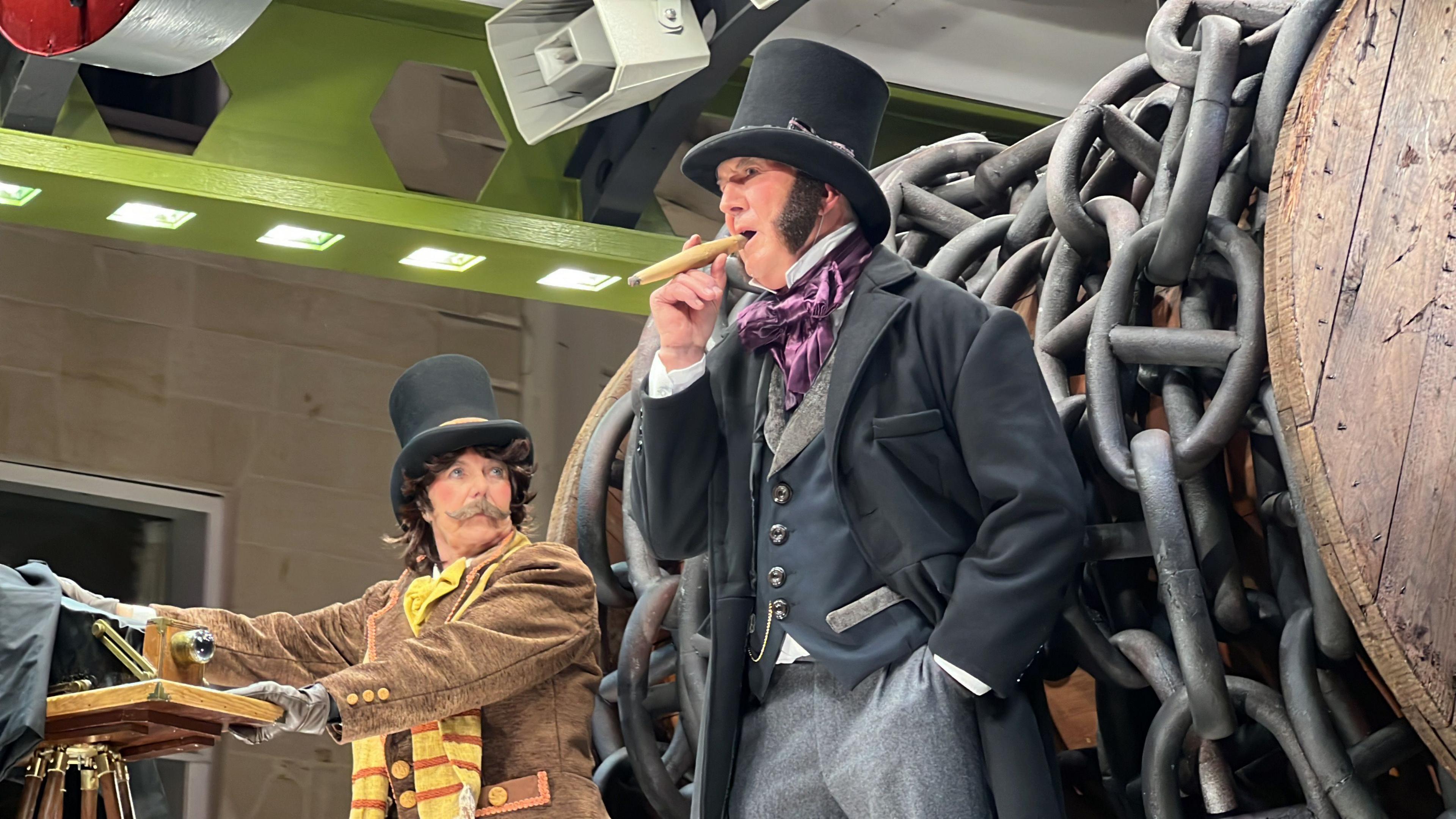 A man dressed as Isambard Kingdom Brunel stands on a carnival float with chains behind him, and a woman dressed as a man stood beside him.