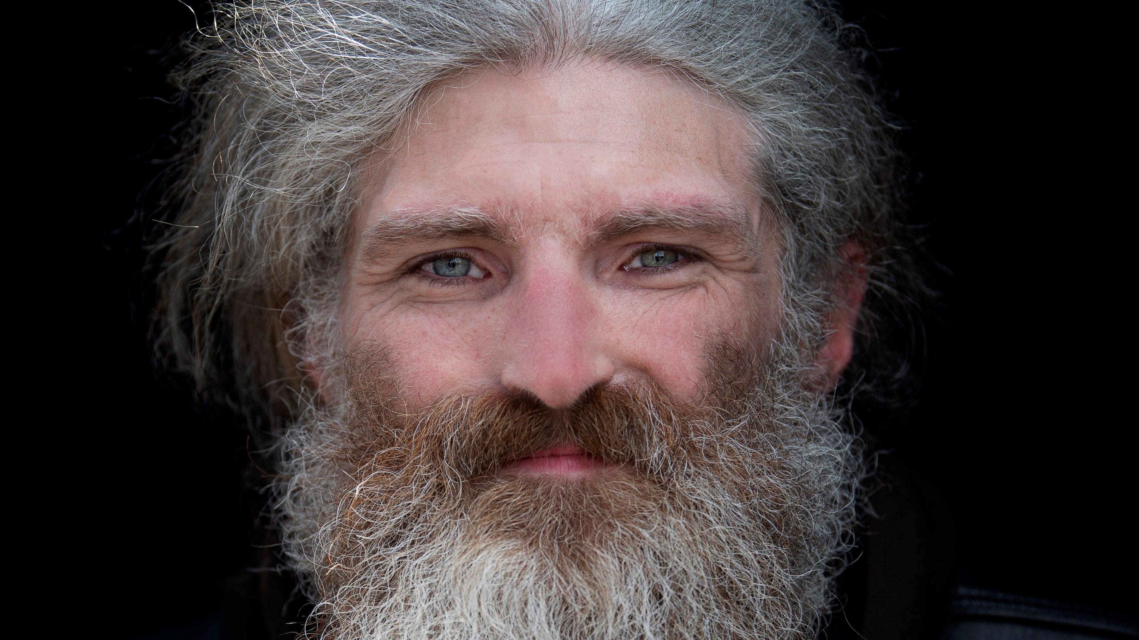 Long grey haired and bearded man with piercing blue eyes looking at the camera.