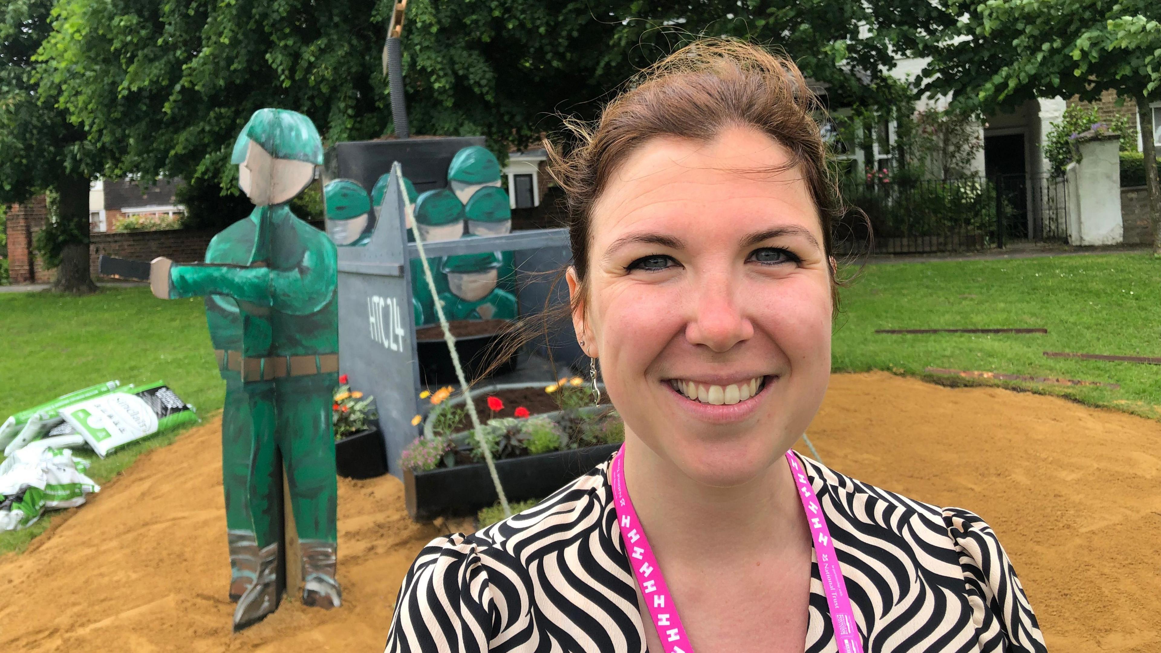 Natasha Pierson standing in front of the landing craft, made with recycled materials and festooned with flowers