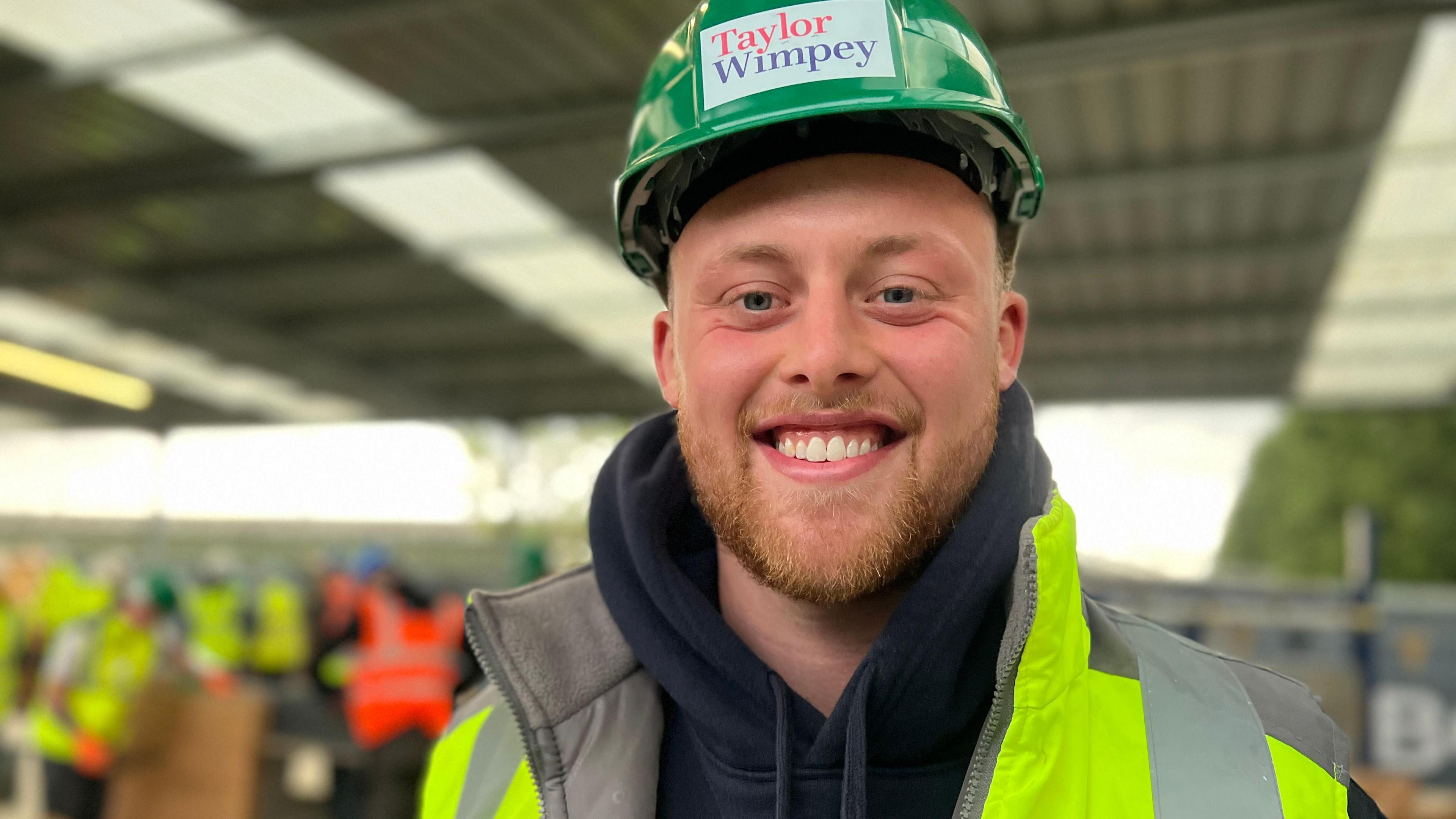 Toby Egan, 23, in a high-vis jacket and helmet, smiling