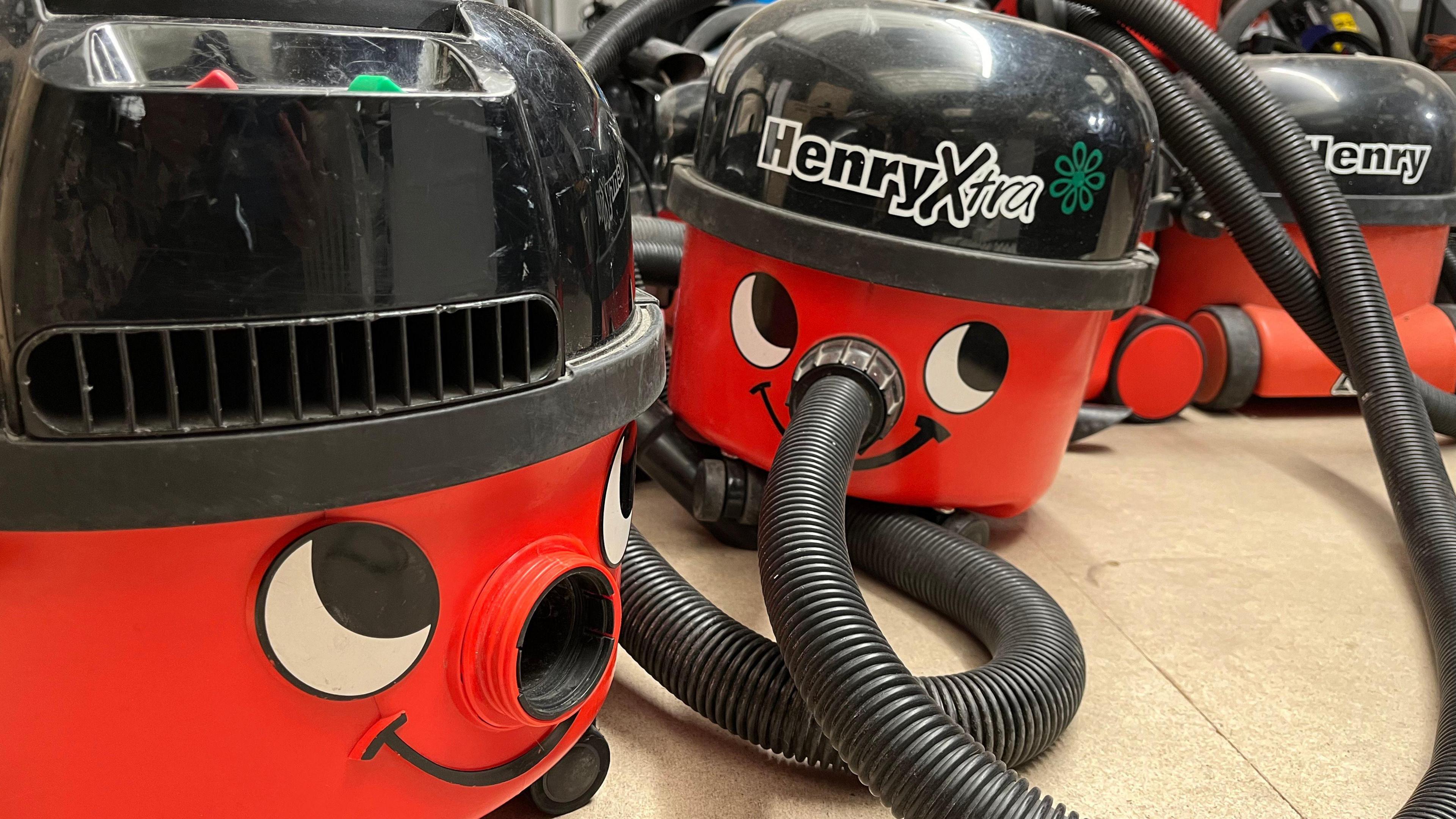 A group of the familiar red smiling Henry vacuum cleaners