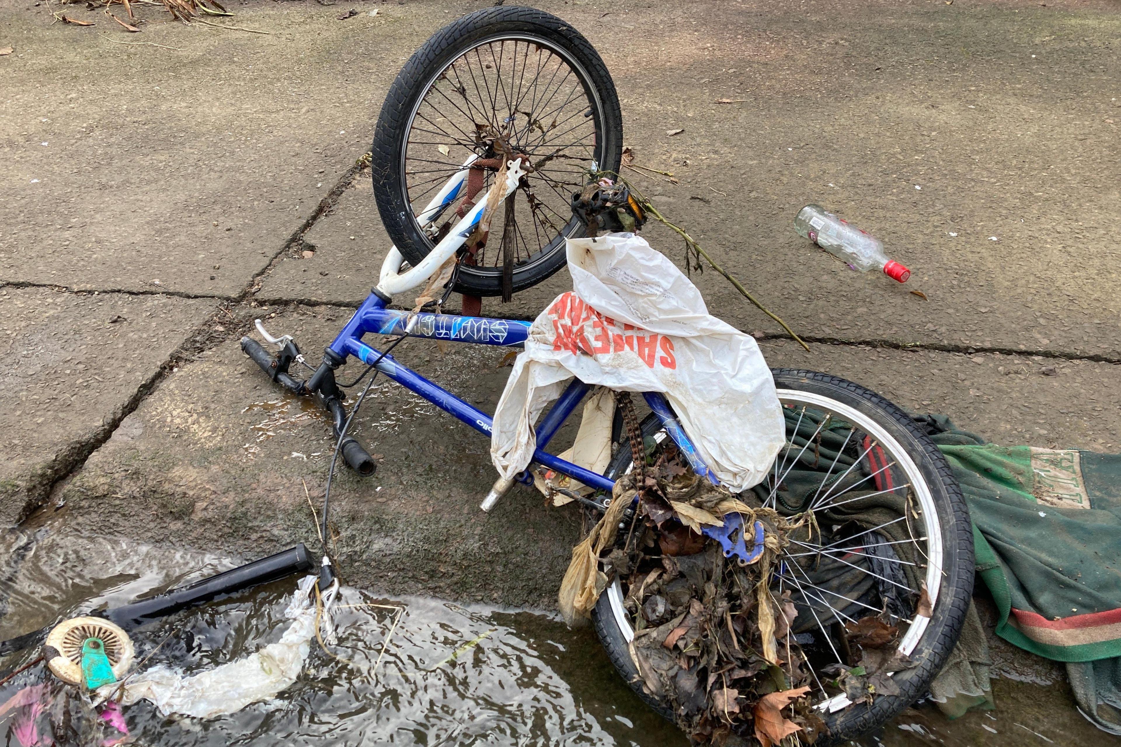 An old blue and white mountain bike is among the junk found along Willow Brook and as seen here plastic bags and old clothes are caught up in it. 