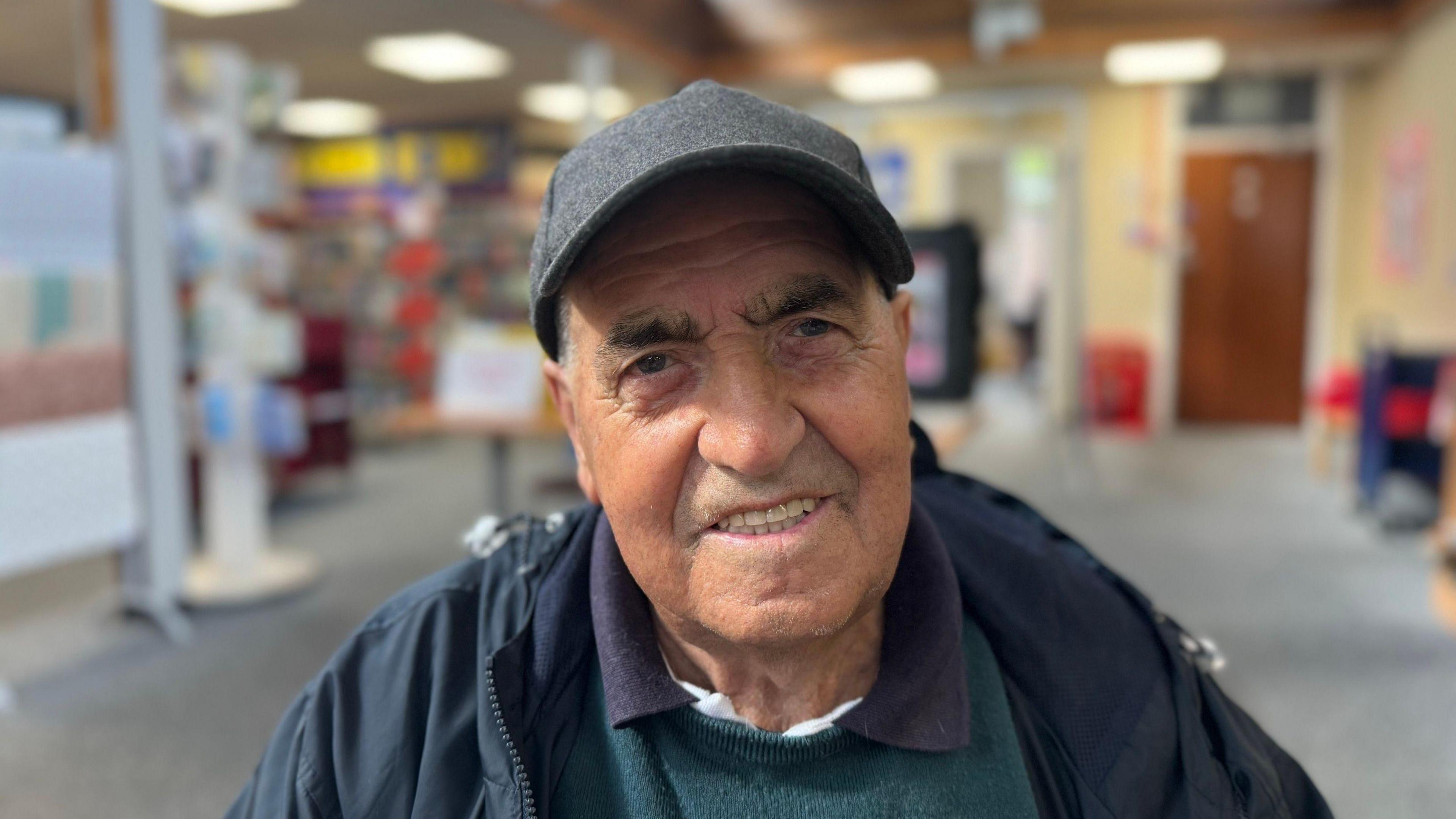 A man sitting in a library wearing a cap