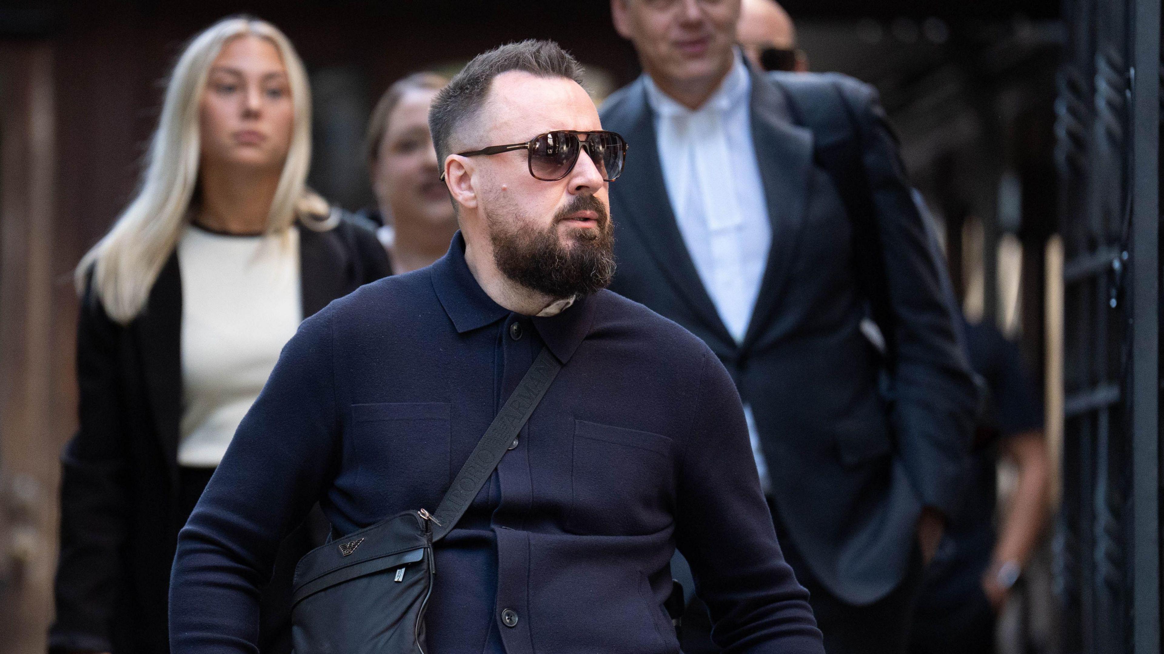 Martin Hibbert outside court in a wheelchair, wearing sunglasses