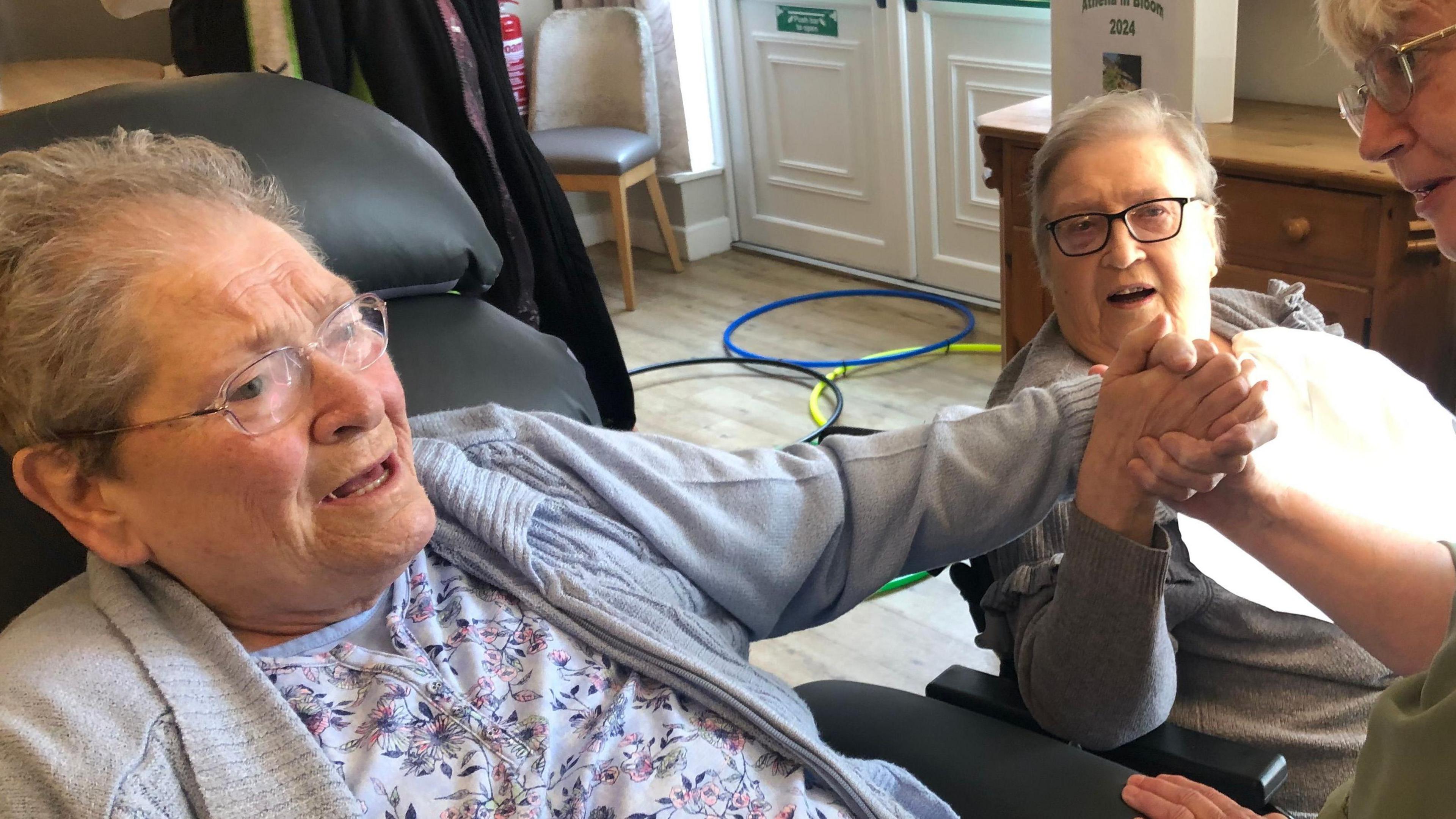 Ruth Bester and Brenda Sired smiling and holding hands after being reunited