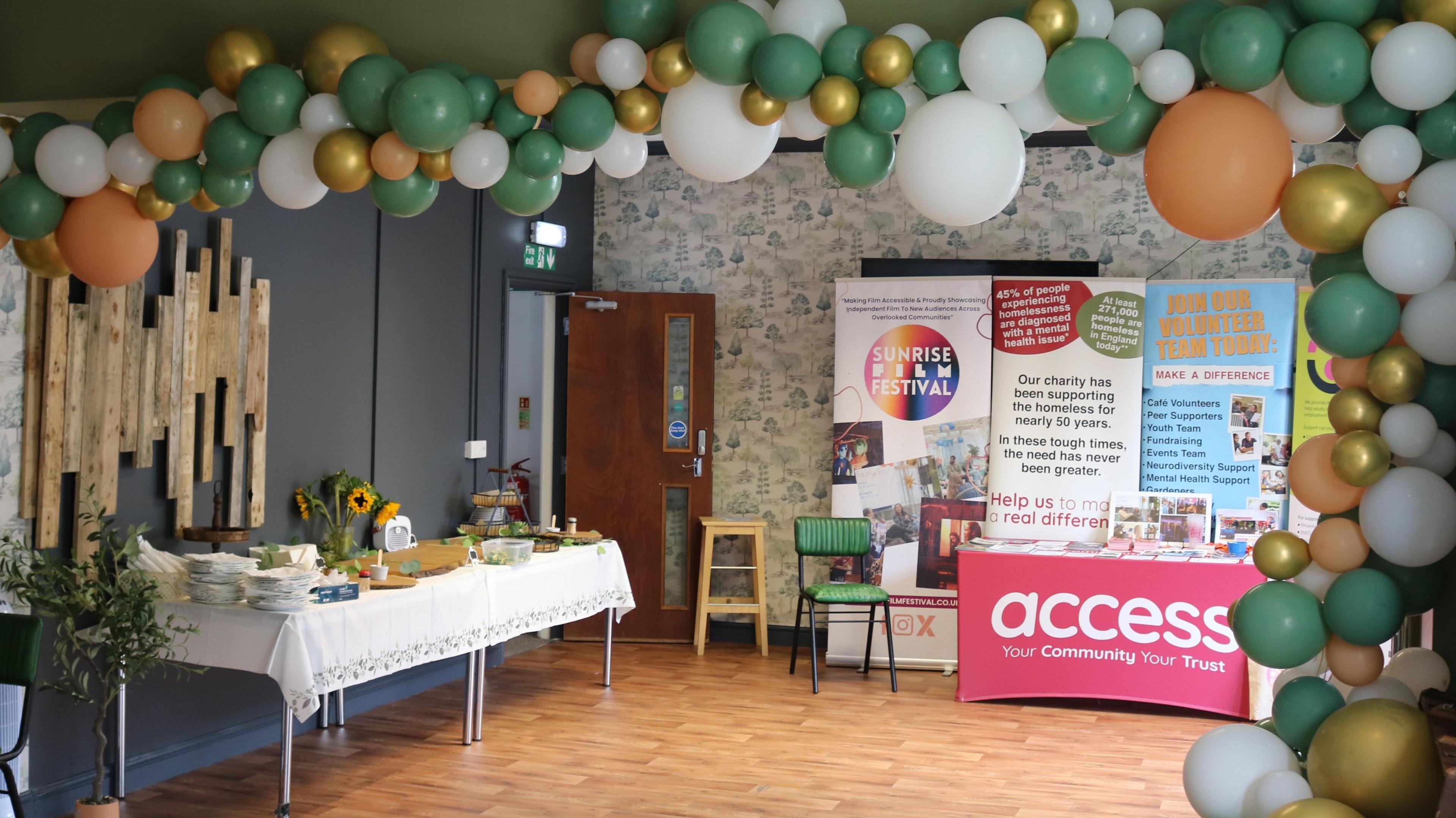 Interior of wellbeing centre showing balloons and table with a white tablecloth plus charity banners.