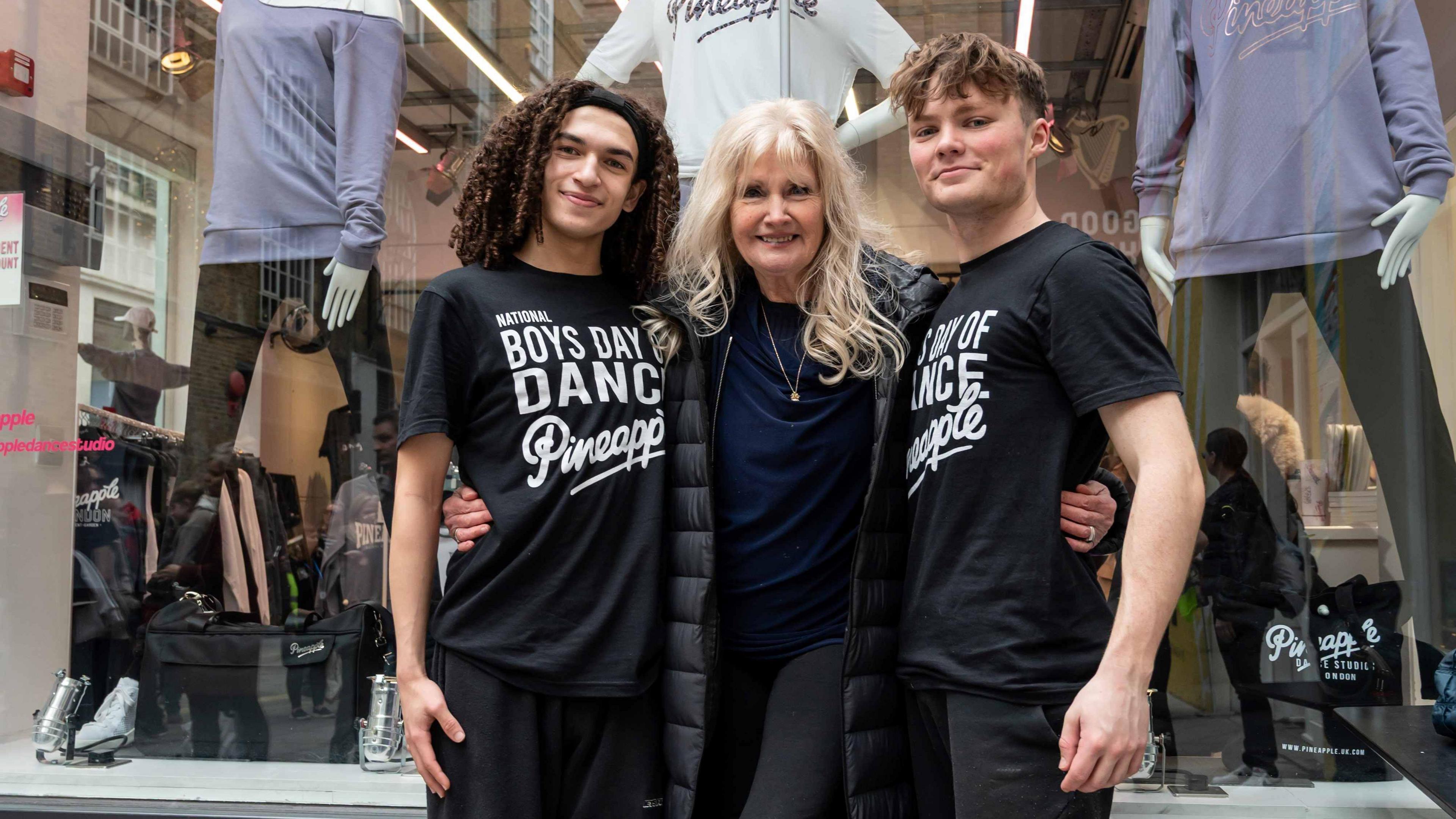 Debbie Moore centre smiling at the camera has long blonde hair and is wearing a navy top. To her left is Corben Heward-Mills and her right Corbin White wearing black t-shirts with white writing on.