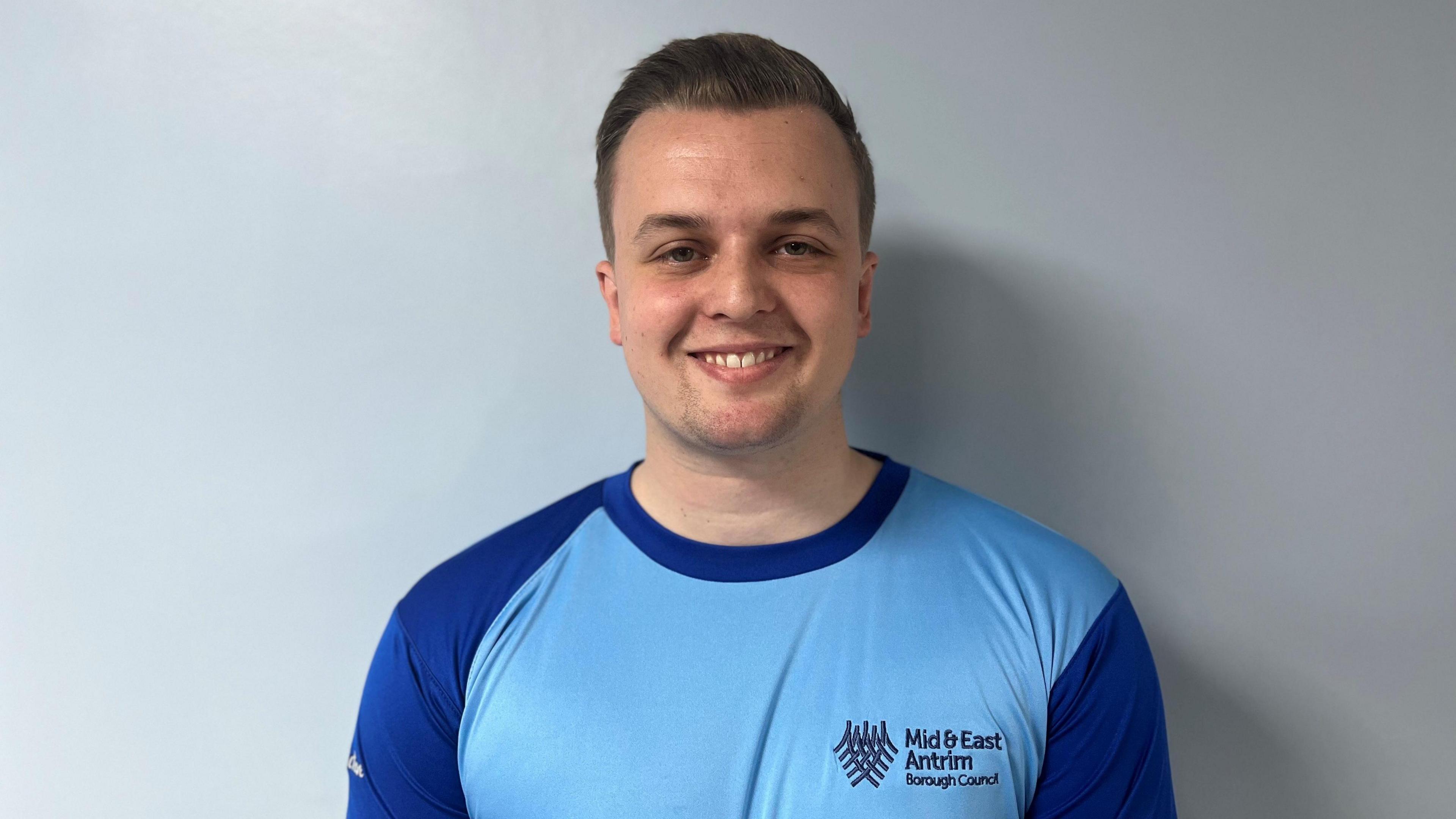 Man with borwn hair wearing a blue top