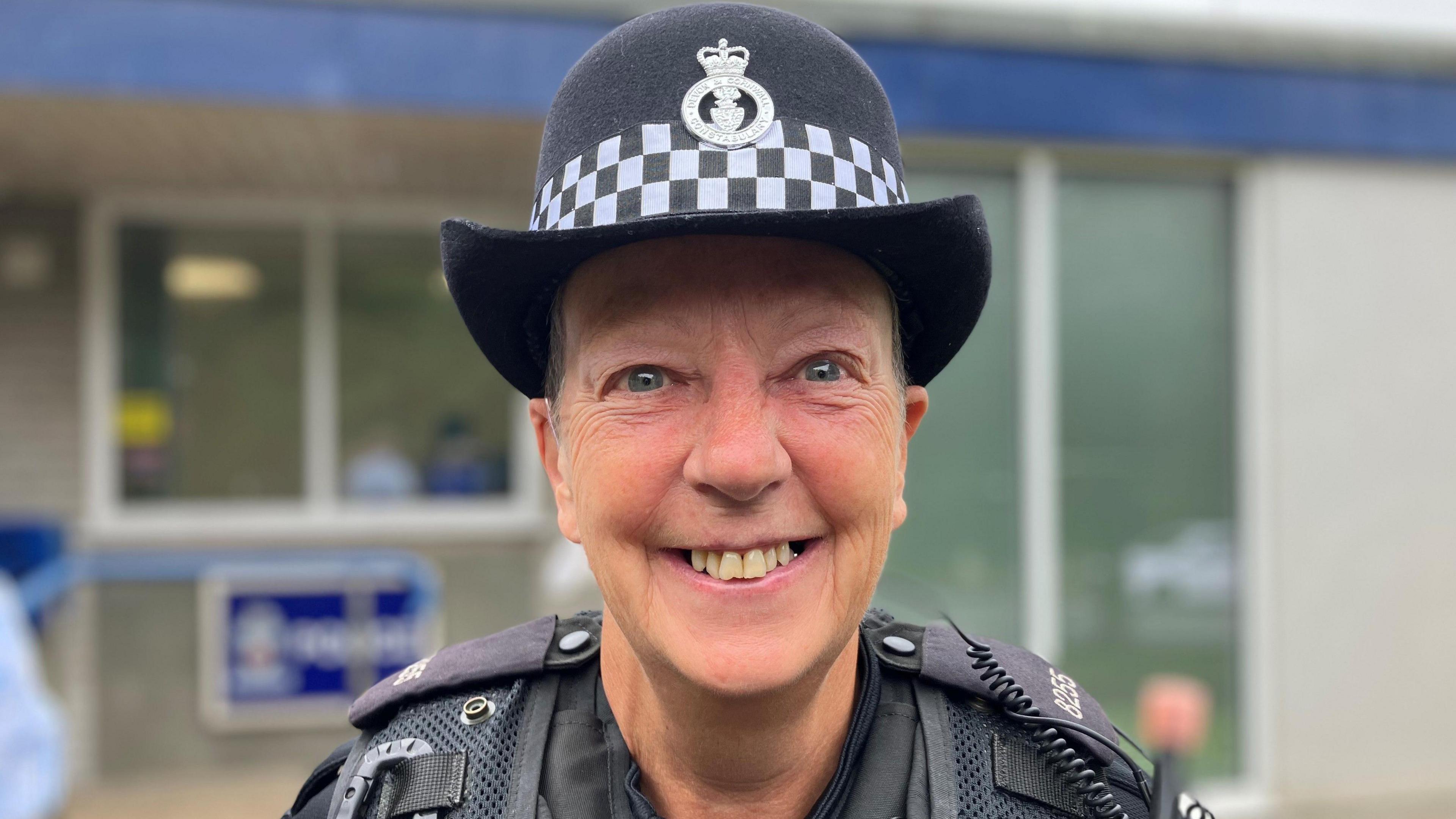 PC Pip Davey is smiling at the camera. She is wearing police uniform and is standing outside a police station.