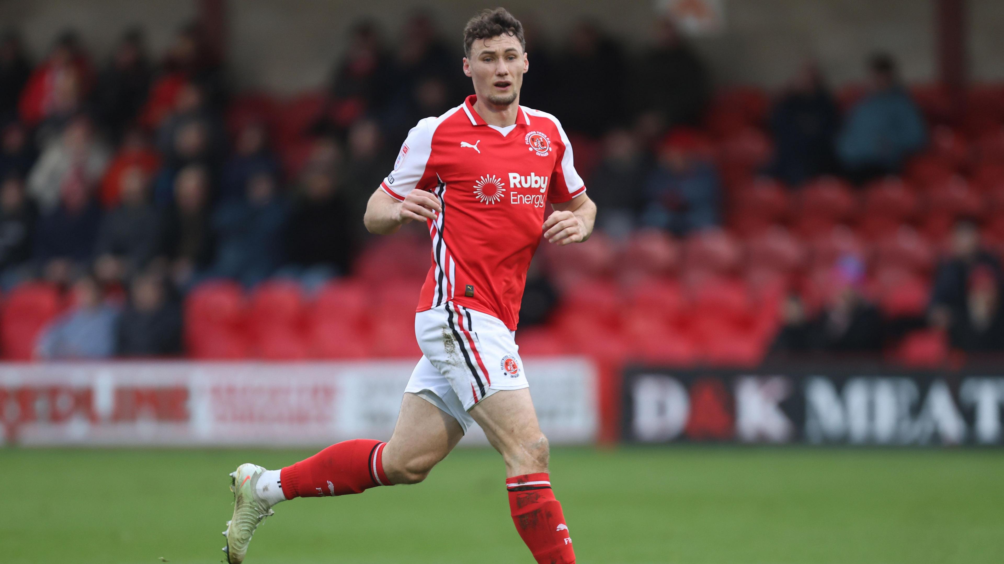 Matty Virtue running and looking forward, wearing Fleetwood home red and white kit