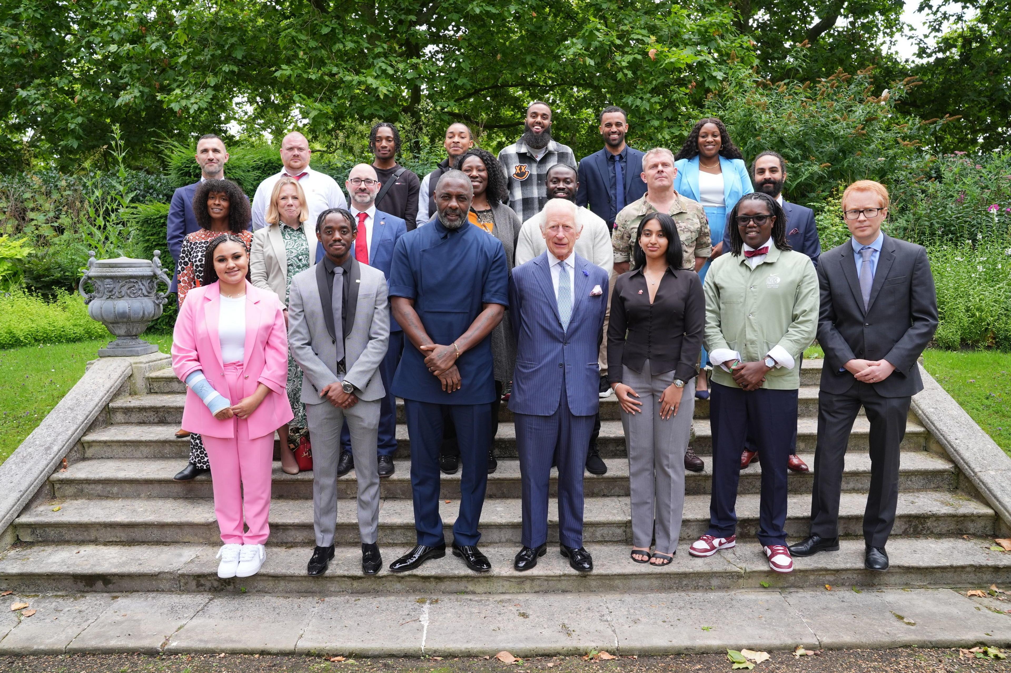 King Charles III in the centre, front row, in a group photo with young people from the King's Trust n the steps with Idris Elba (centre left) and young people attend an event for The King's Trust to discuss youth opportunity, at St James's Palace in central London.