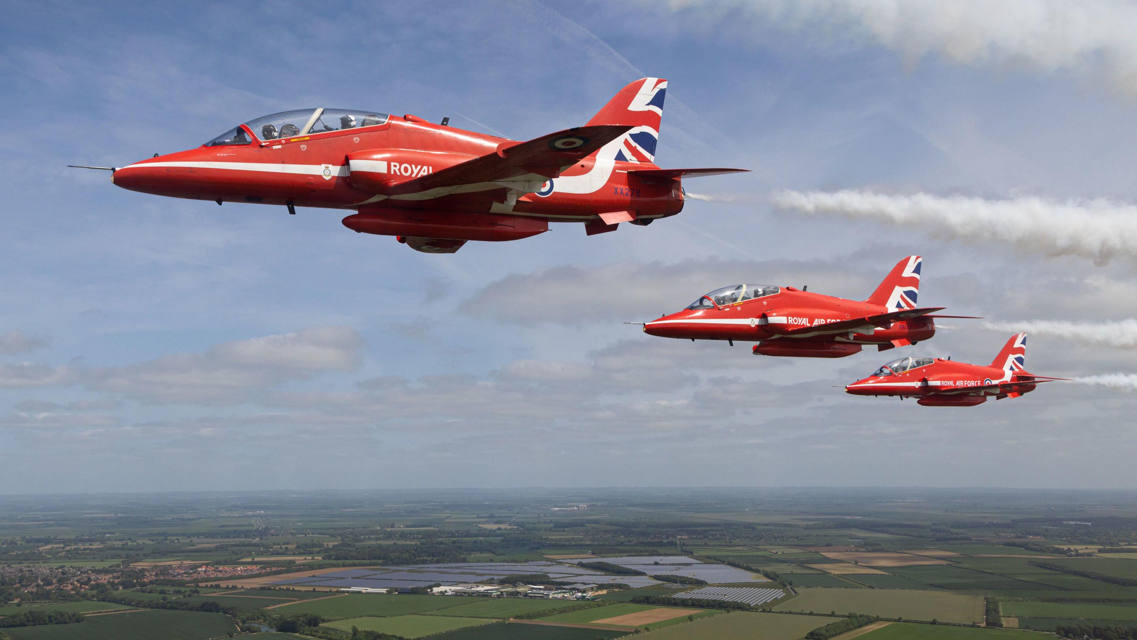 The Red Arrows in flight over countryside