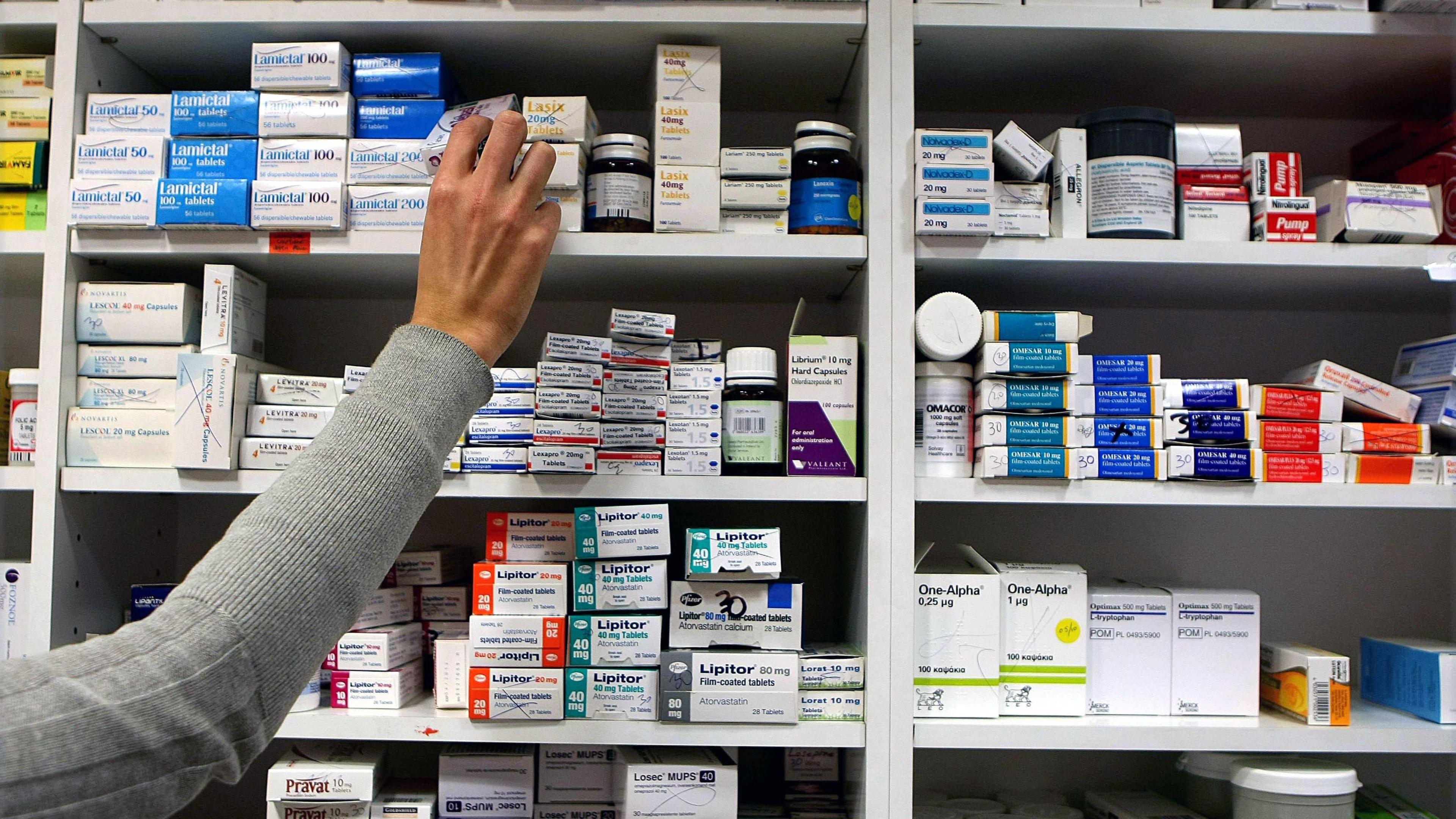 A hand reaching for medication on a shelf