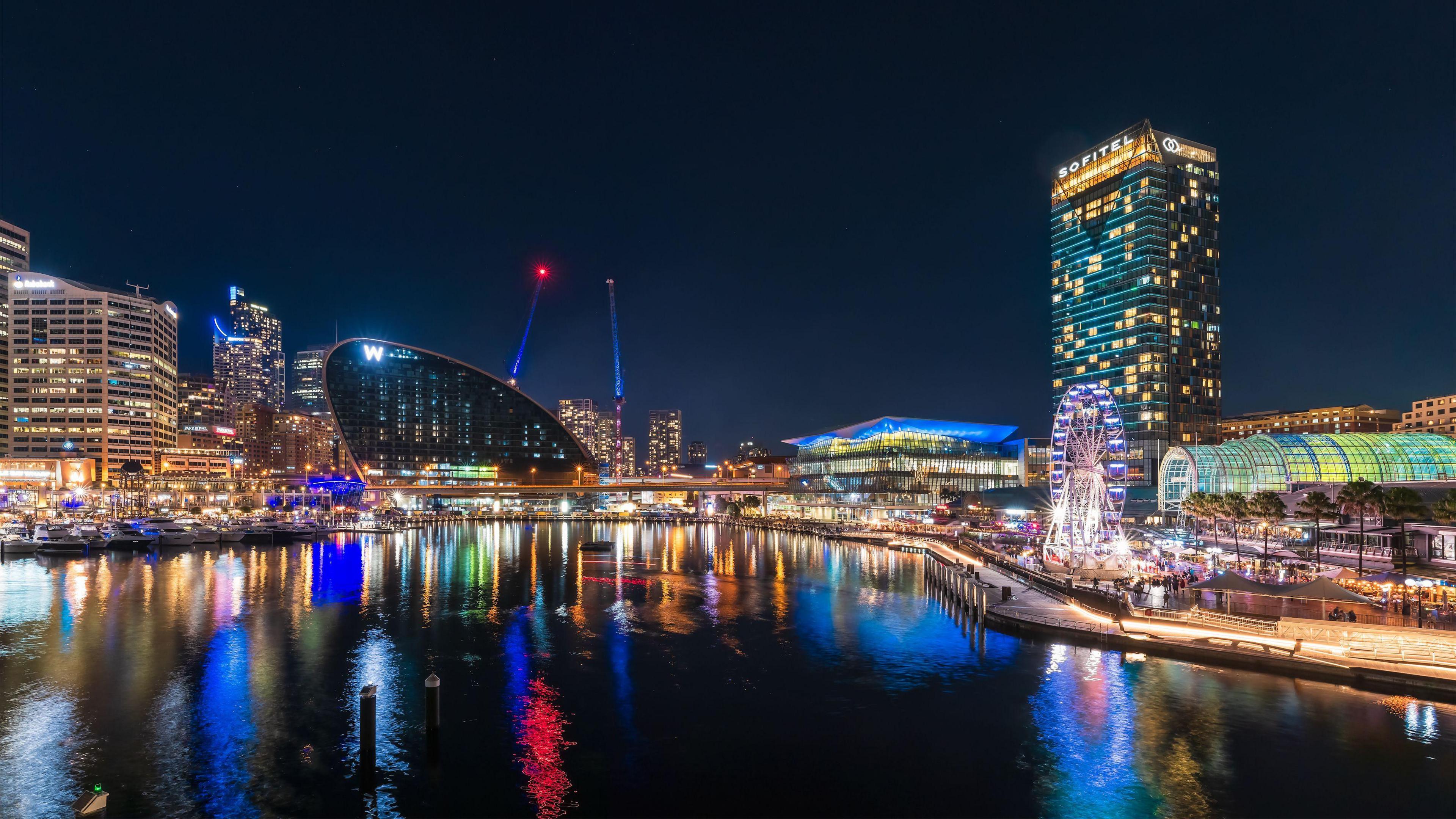 The city of Sydney at night, with buildings lit up and the water at Darling Harbour glistening