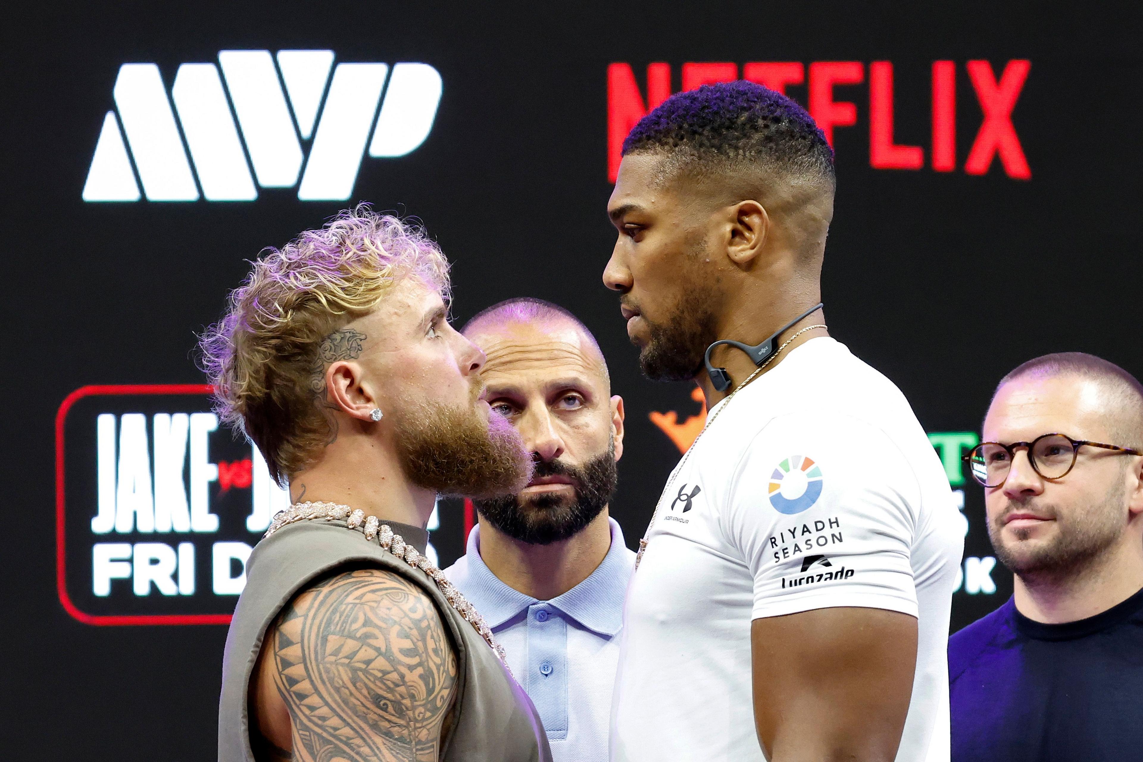 Two athletes facing off during a pre-fight event, standing close together on stage with sponsor logos including MVP and Netflix visible in the background
