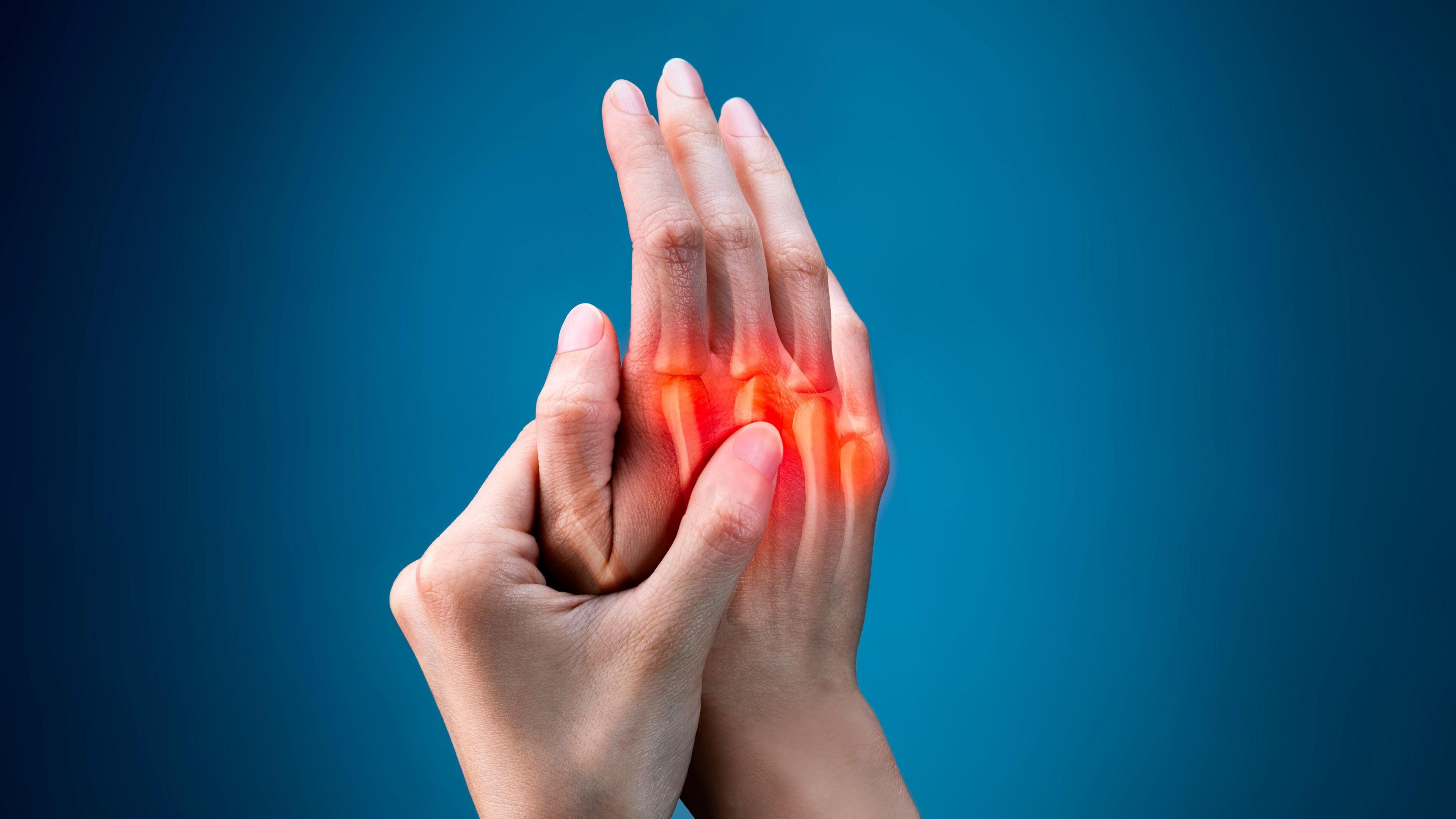 A pair of hands held together with x-ray imaging to show the bones inside one of the hands which is glowing red. They are held up against a blue background.