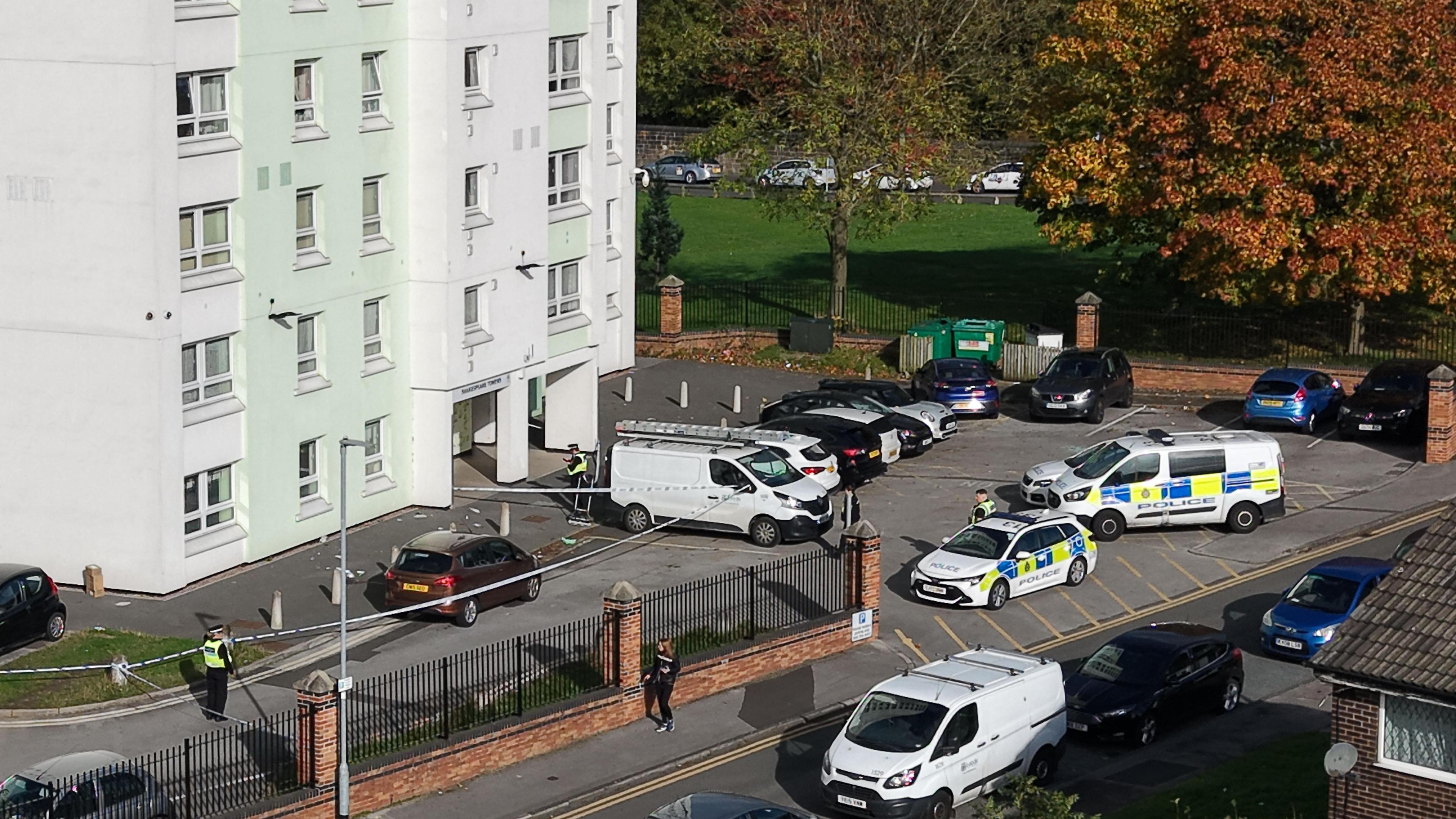 Police cars and cordon with two officers outside the front of a tower block