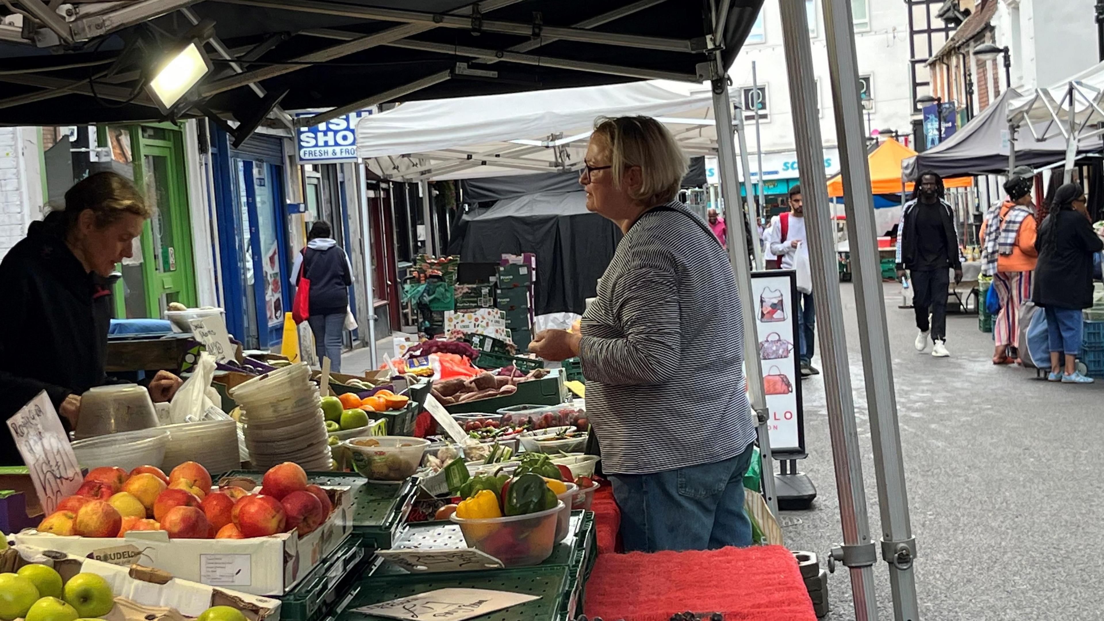 Woman at a fruit and veg stall at Surrey Street Market in Croydon.