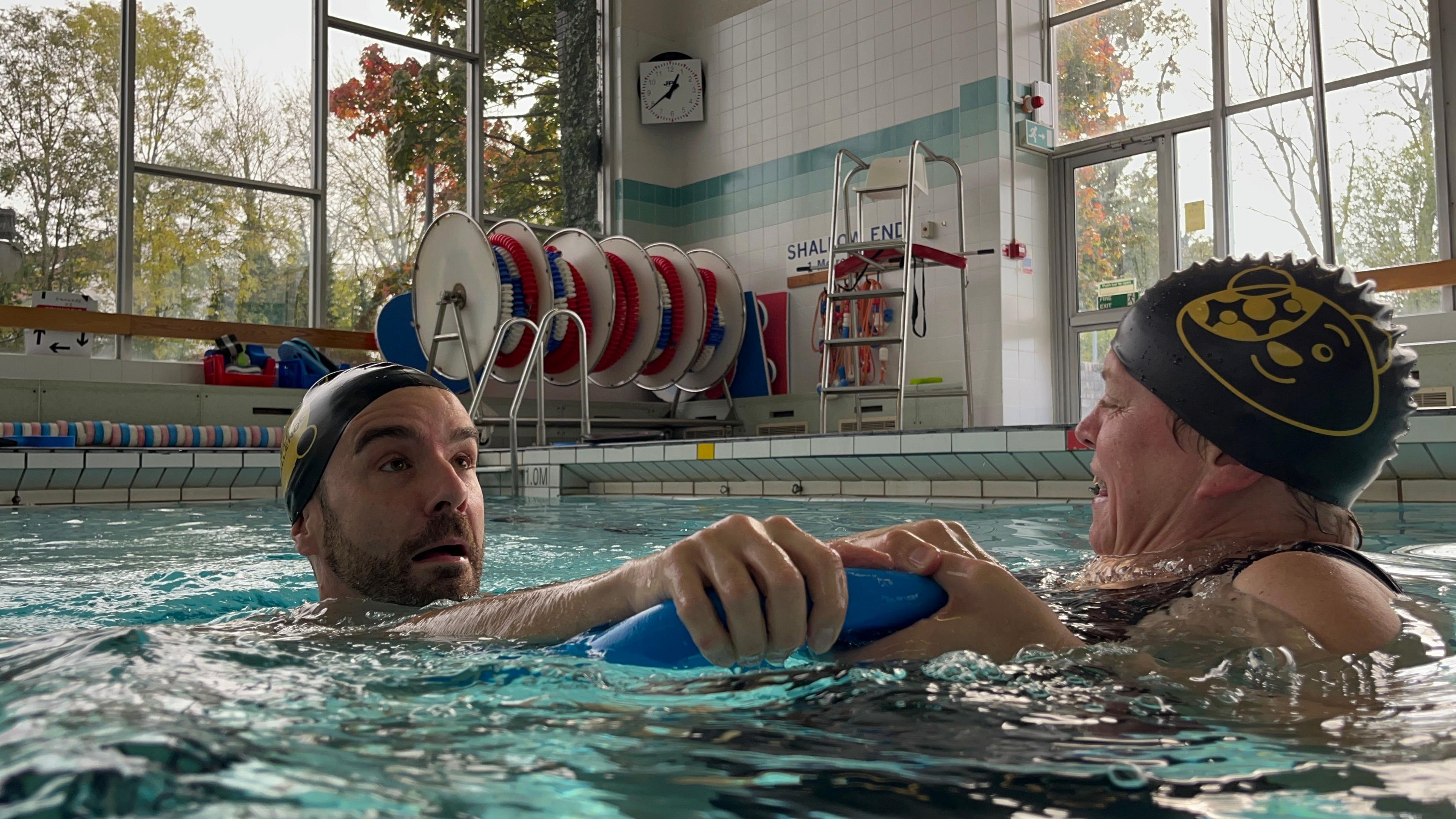 Adam Dowling with a swimming cap on, holding a floaty while looking terrified during his swimming lesson.