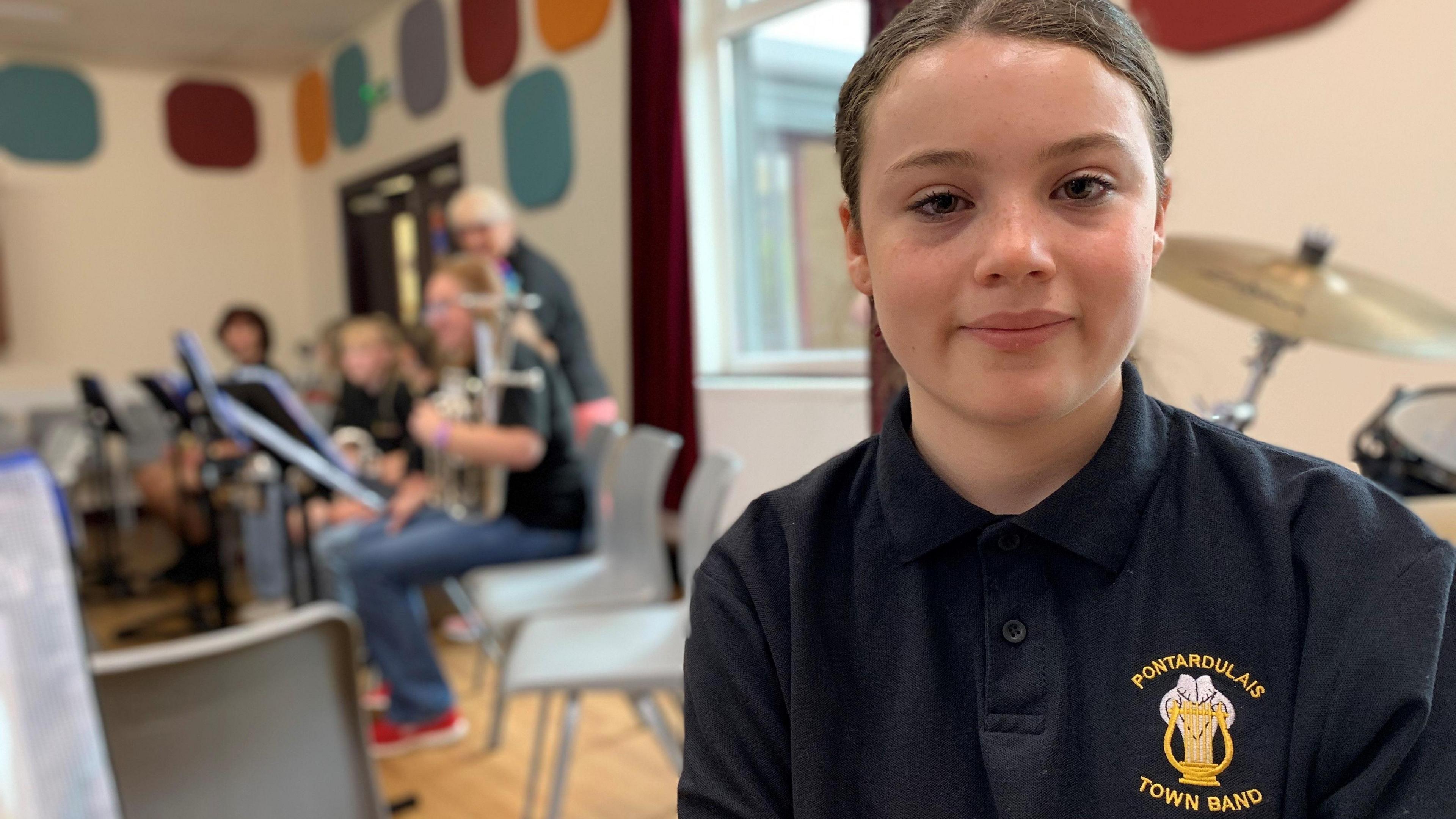 Cerys, a young musician with Pontardulais Town Band, with other musicians in the background