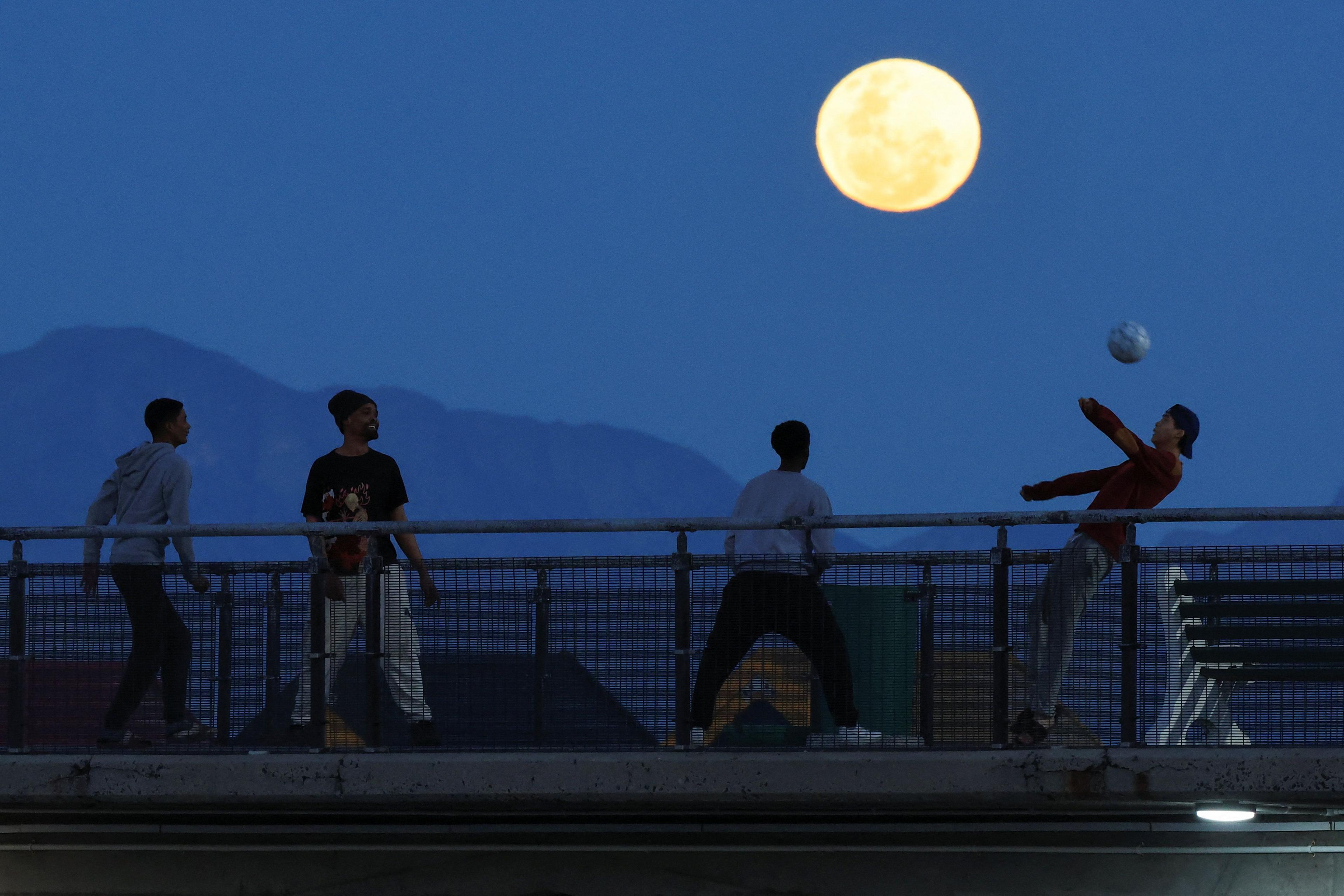 Youth play soccer as the full moon rises over Muizenberg, Cape Town, South Africa.