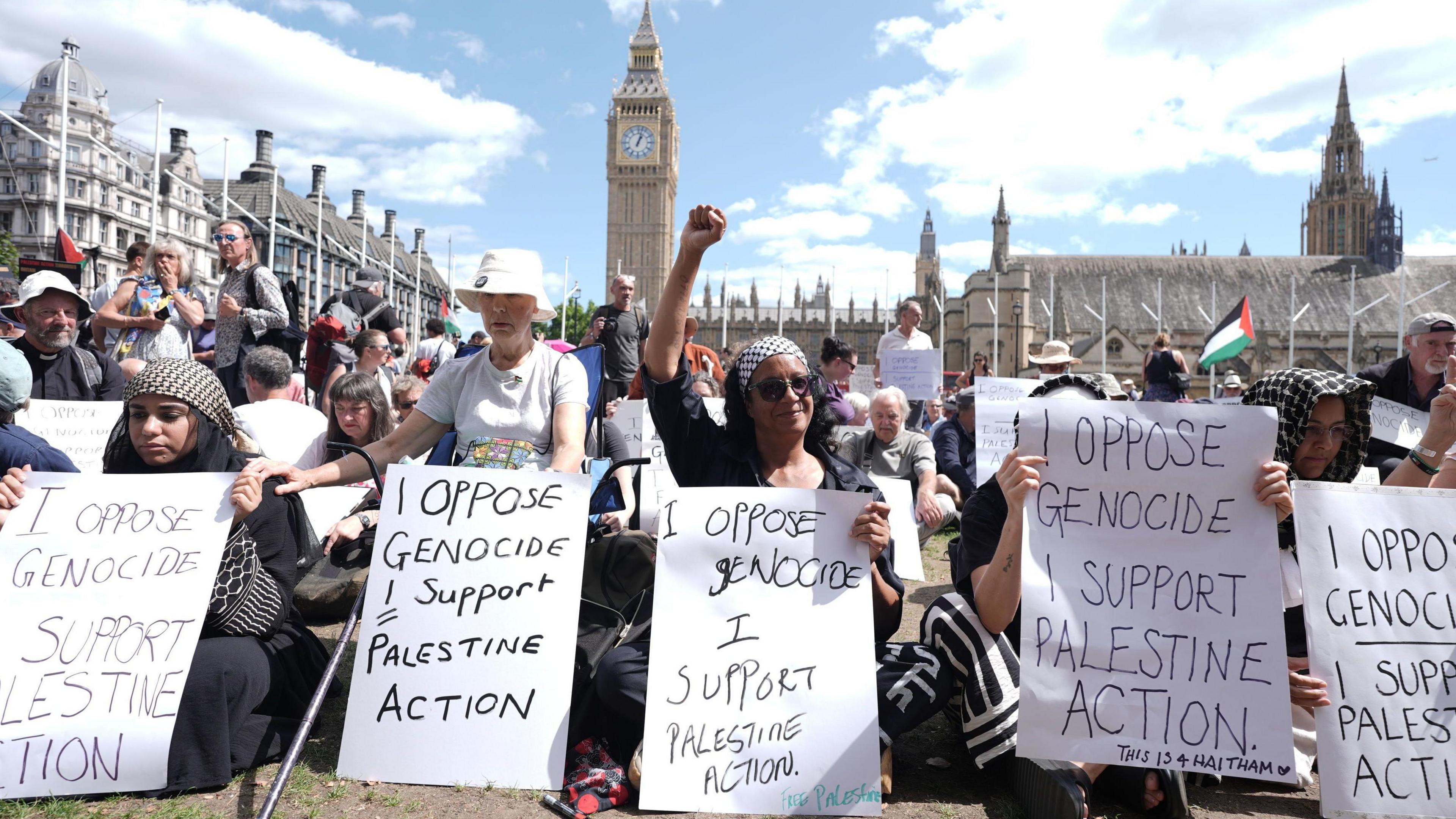 Supporters of Palestine Action hold up signs at a protest in Parliament Square, Westminster