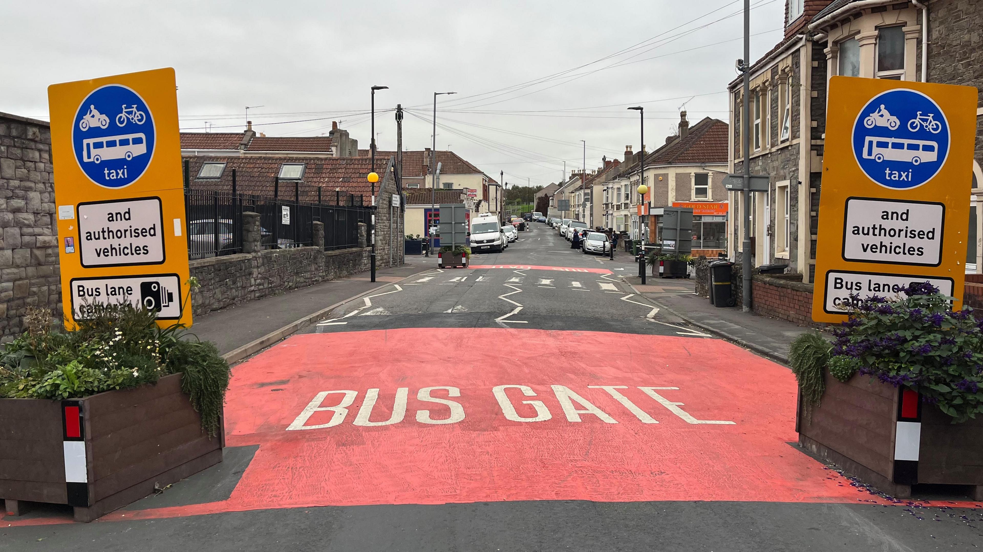 A street in Barton Hill, where "bus gate" has been spray painted onto the road surface. Signs on either side of the road say that only authorised vehicles are allowed through. There are terraced houses on one side of the road and a Chinese takeaway in the distance.