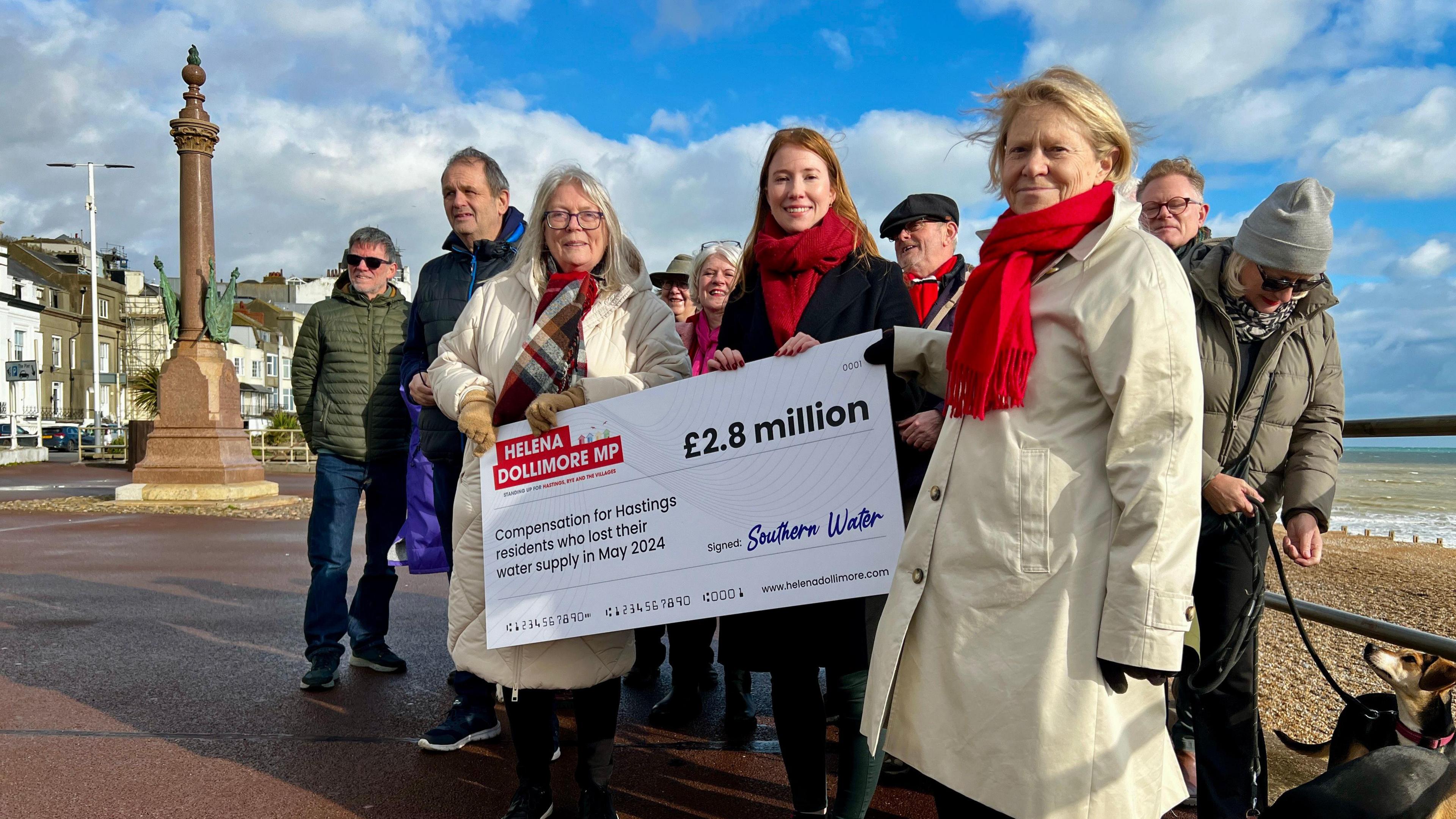 Helena Dollimore stands on Hastings seafront with some of her constituents, holding a giant cheque for £2.8m from Southern Water.