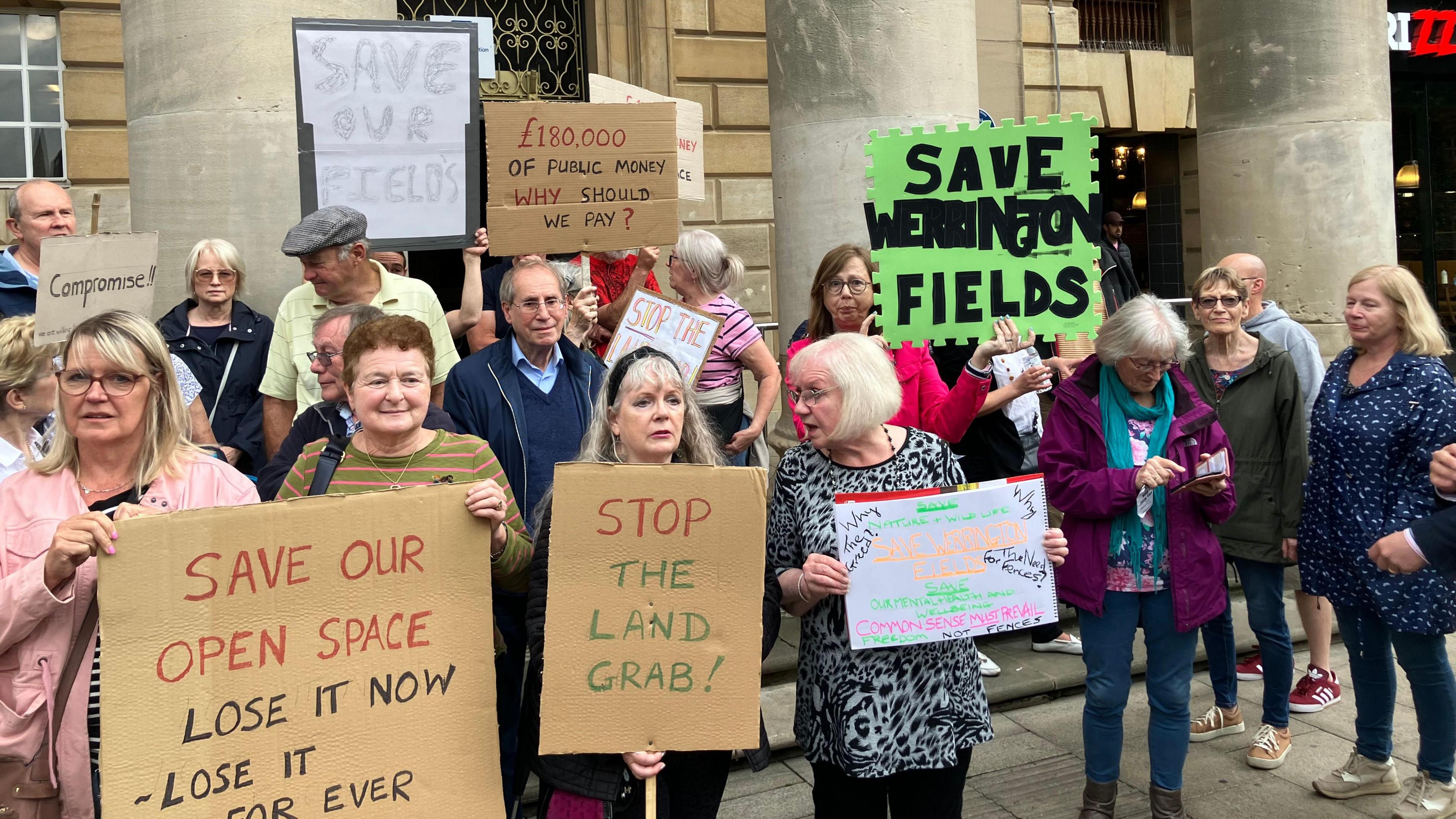 Protesters holding signs that read "Save our open space" and "Stop the land grab" 