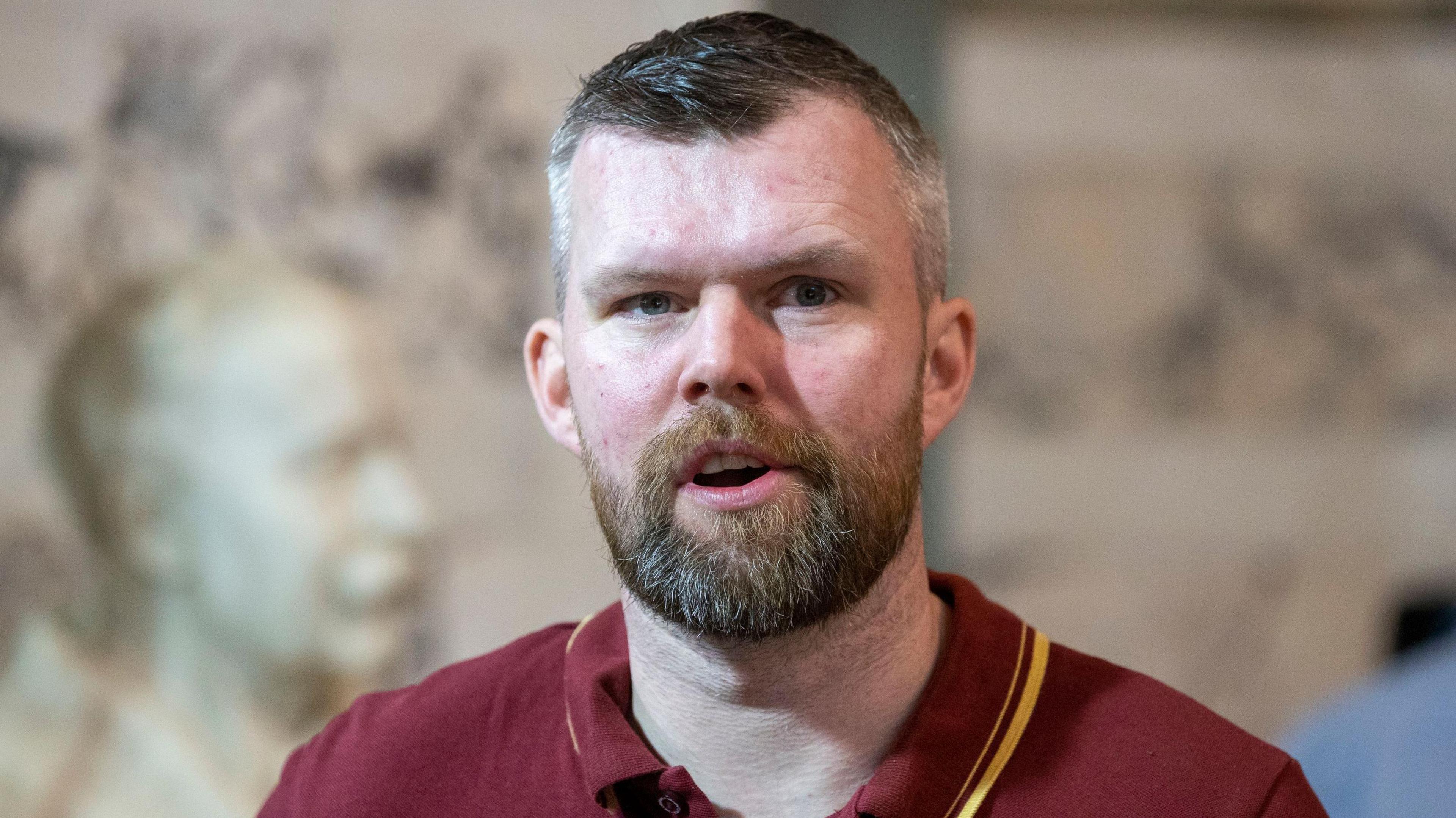 Gerry Carroll -  a greying haired man with a beard wears a maroon polo shirt