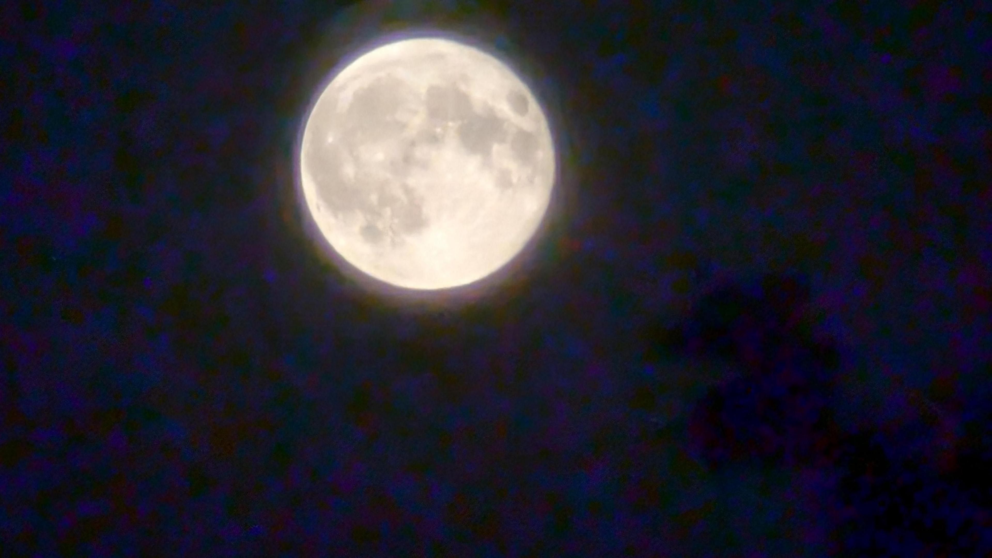 A brighter picture of a shining moon across a night time sky. This is a more fuzzy image. 