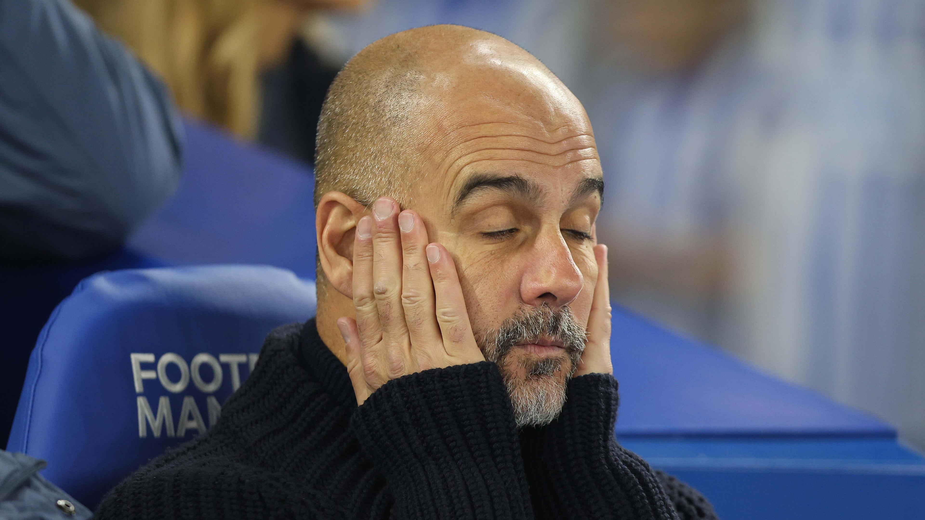 Pep Guardiola holds his head in his hands on the bench during Manchester City's defeat at Brighton on Saturday