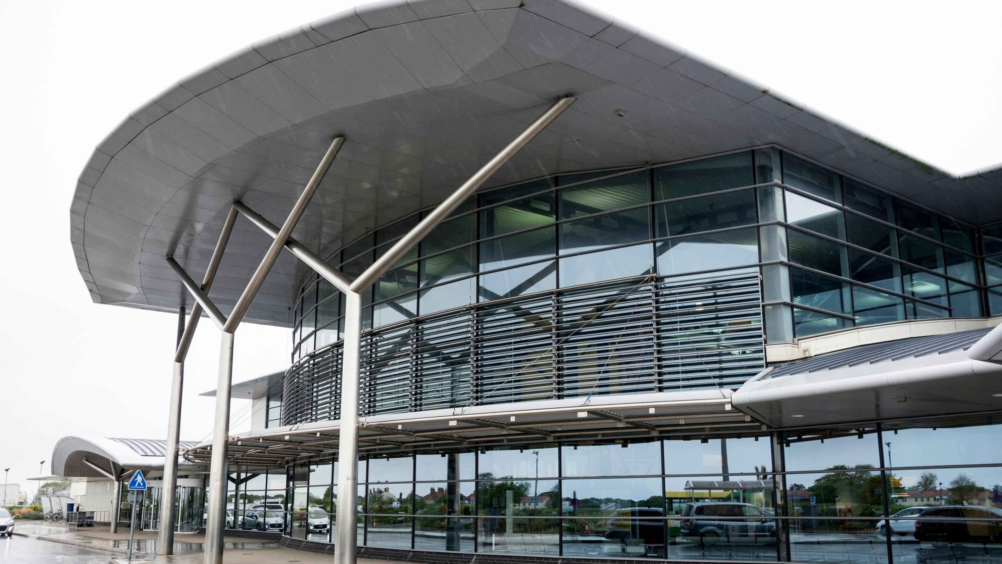 A glass building with metal pylons holding up an awning. 