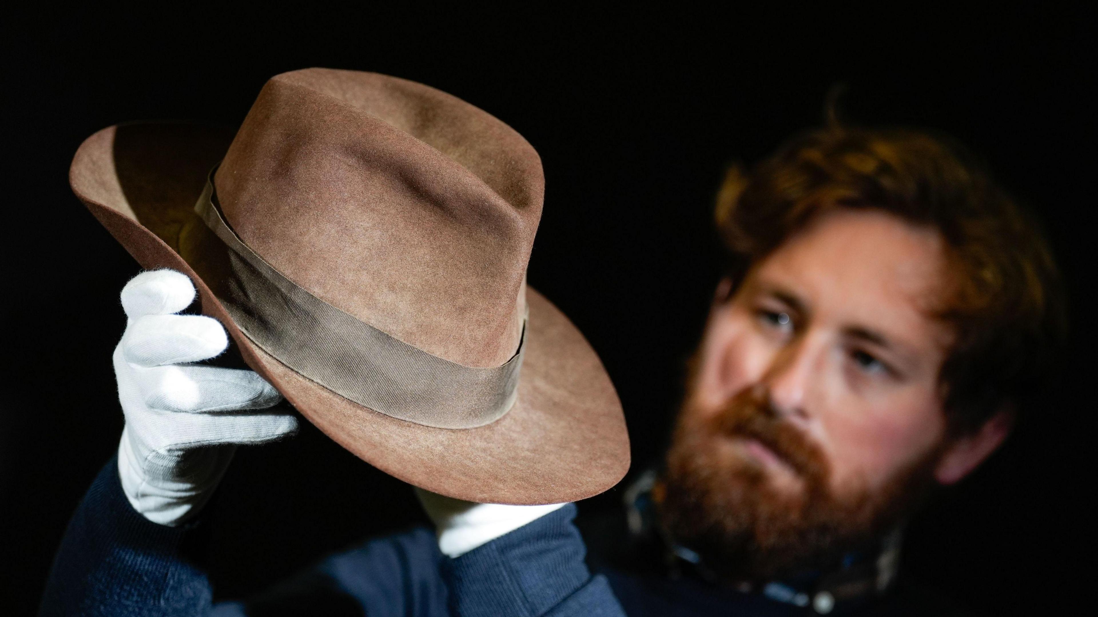 A Propstore employee looks at Indiana Jones' (Harrison Ford) Fedora from the 1984 film 'Indiana Jones and the Temple of Doom' (estimate £150,000 - 300,000).
