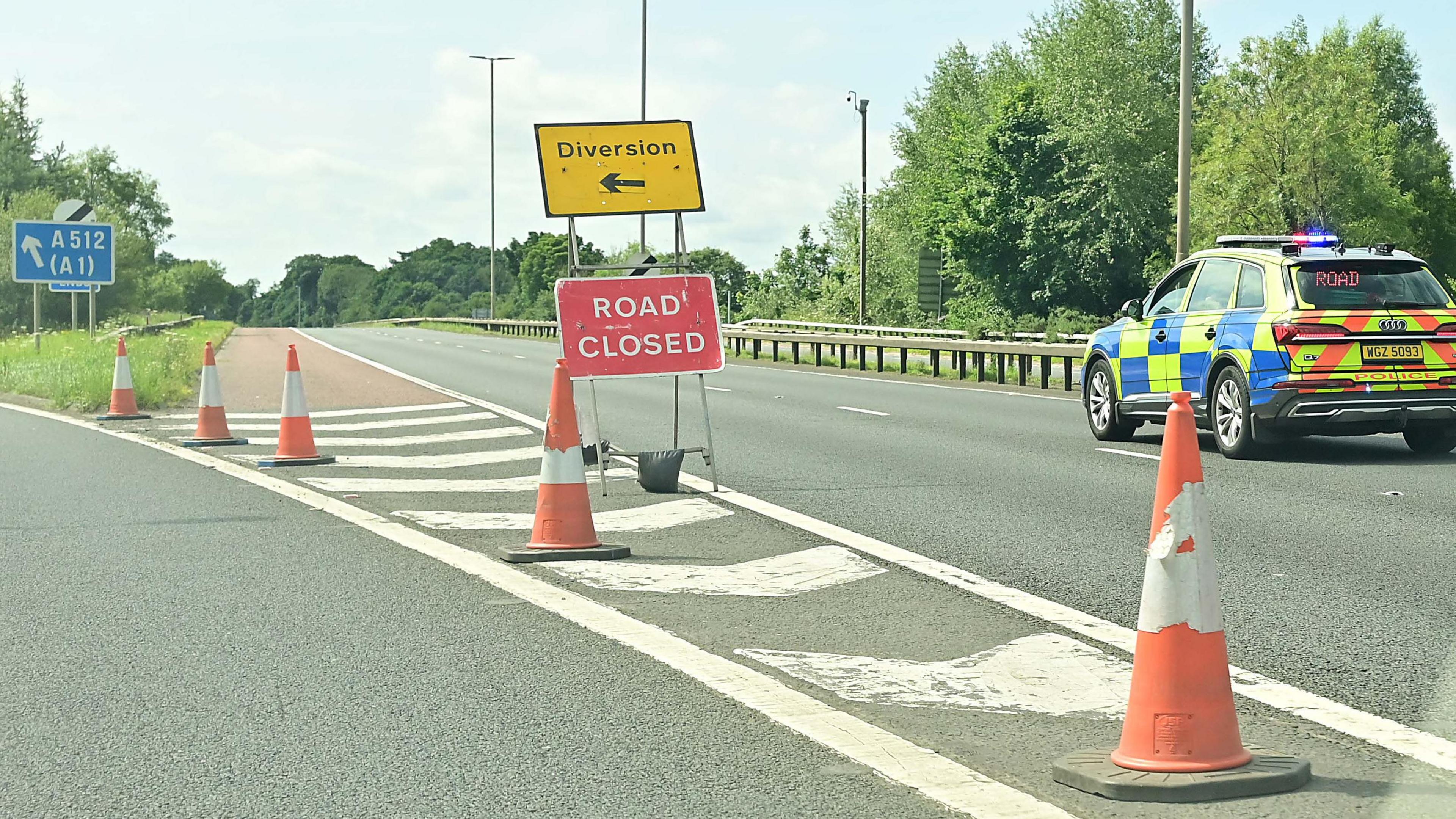 A stationary police car parked beside a Road Closed sign on the M1