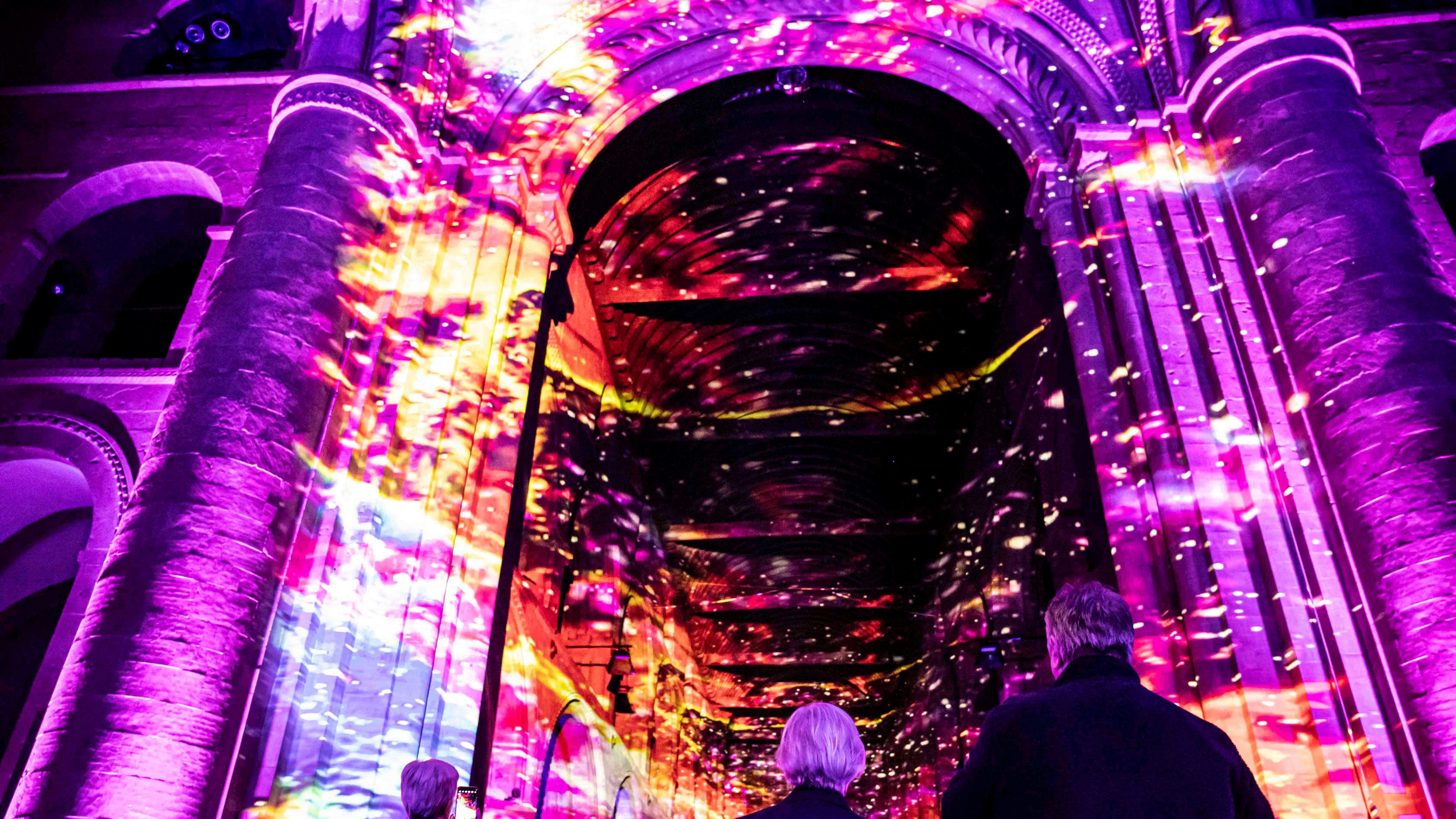 A colourful light installation set against the ceiling in a church.