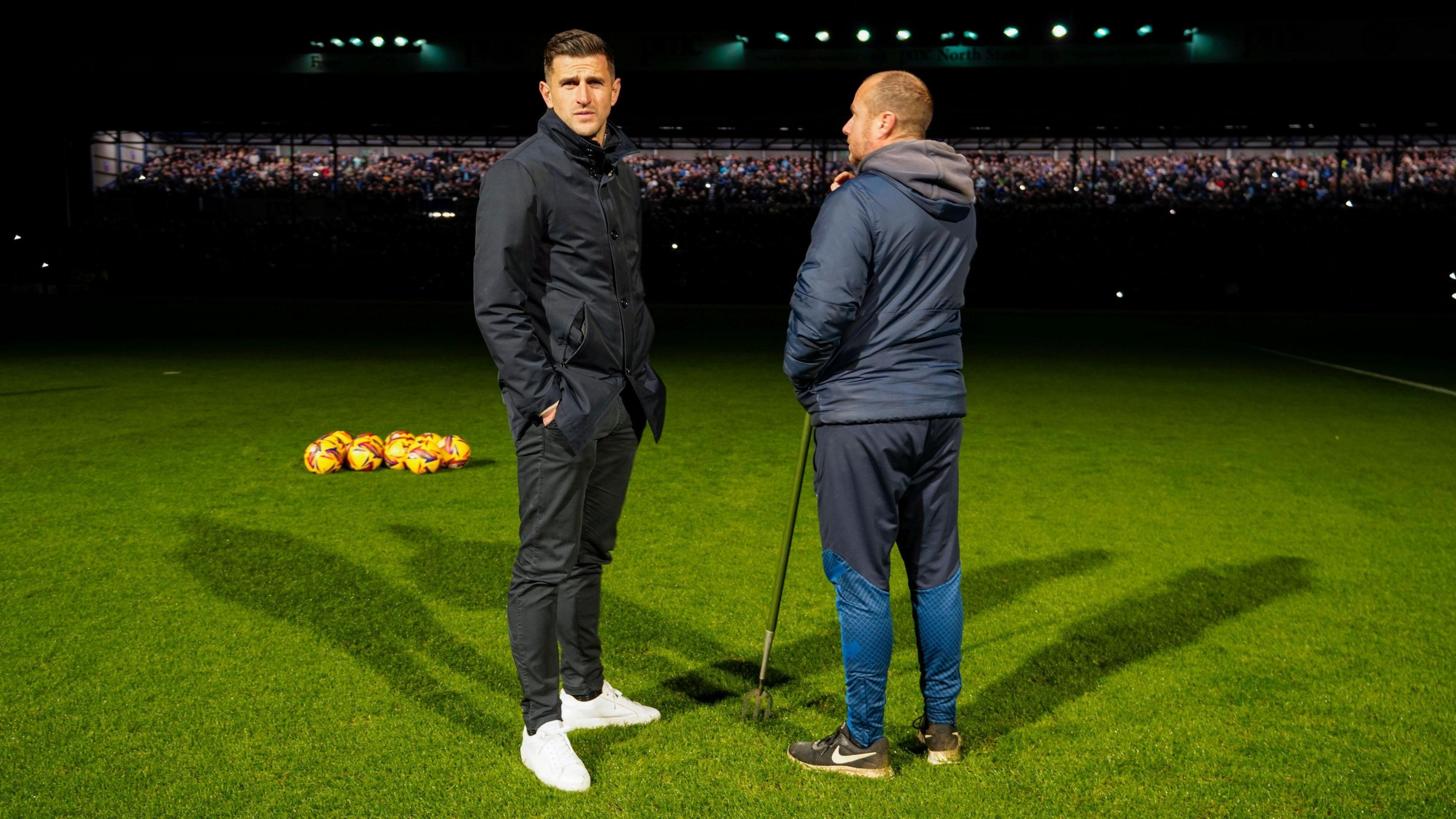 Portsmouth manager John Mousinho stands in front of an unlit stand at Fratton Park